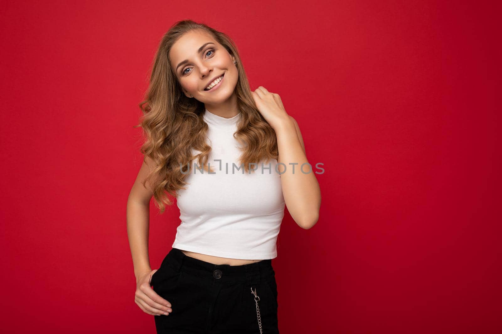 Photo portrait of young sexy beautiful attractive positive smiling blonde woman wearing white top isolated over red background with copy space.