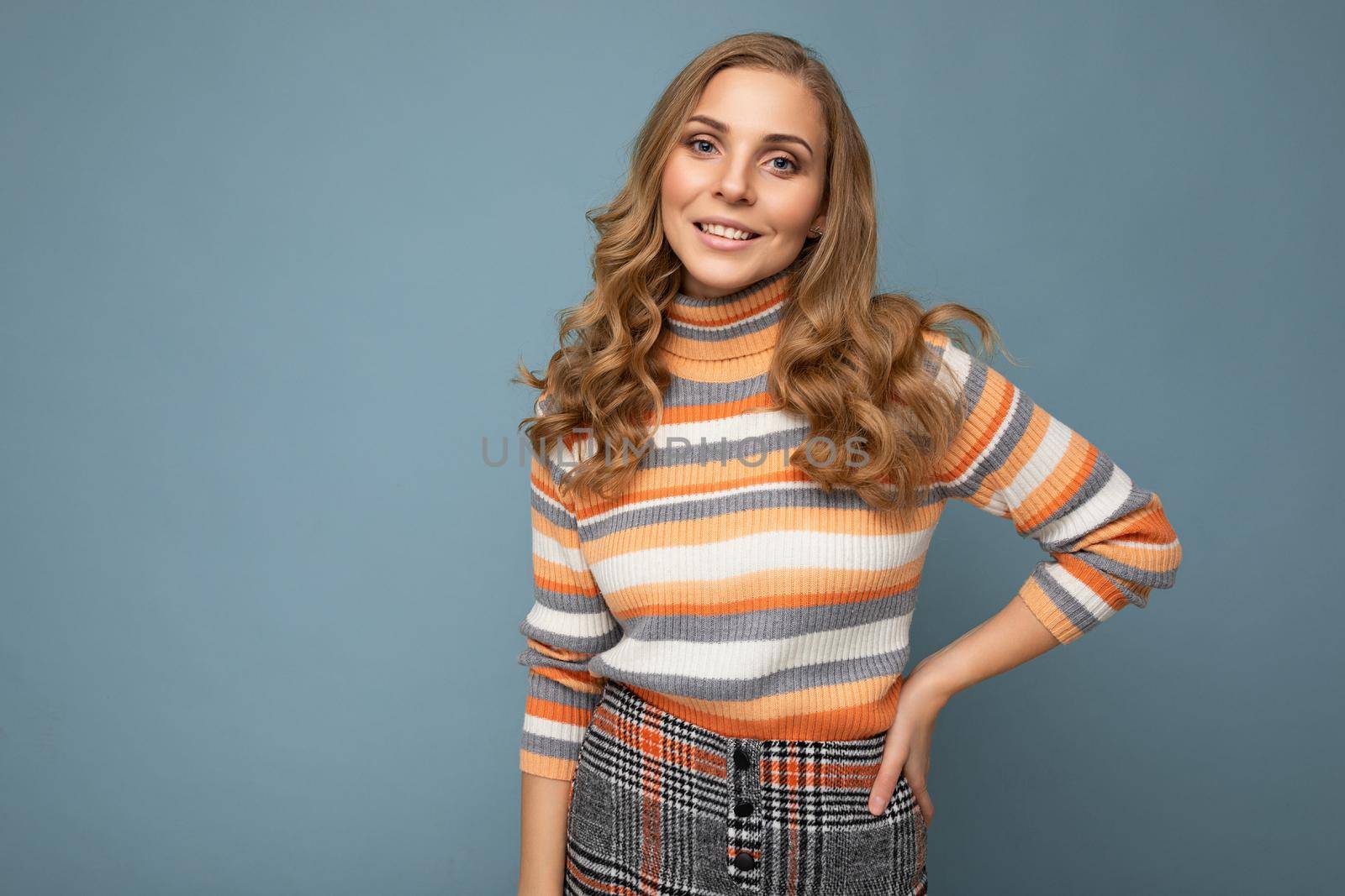 Photo portrait of young beautiful nice positive smiling blonde woman wearing striped pullover isolated over blue background with copy space.