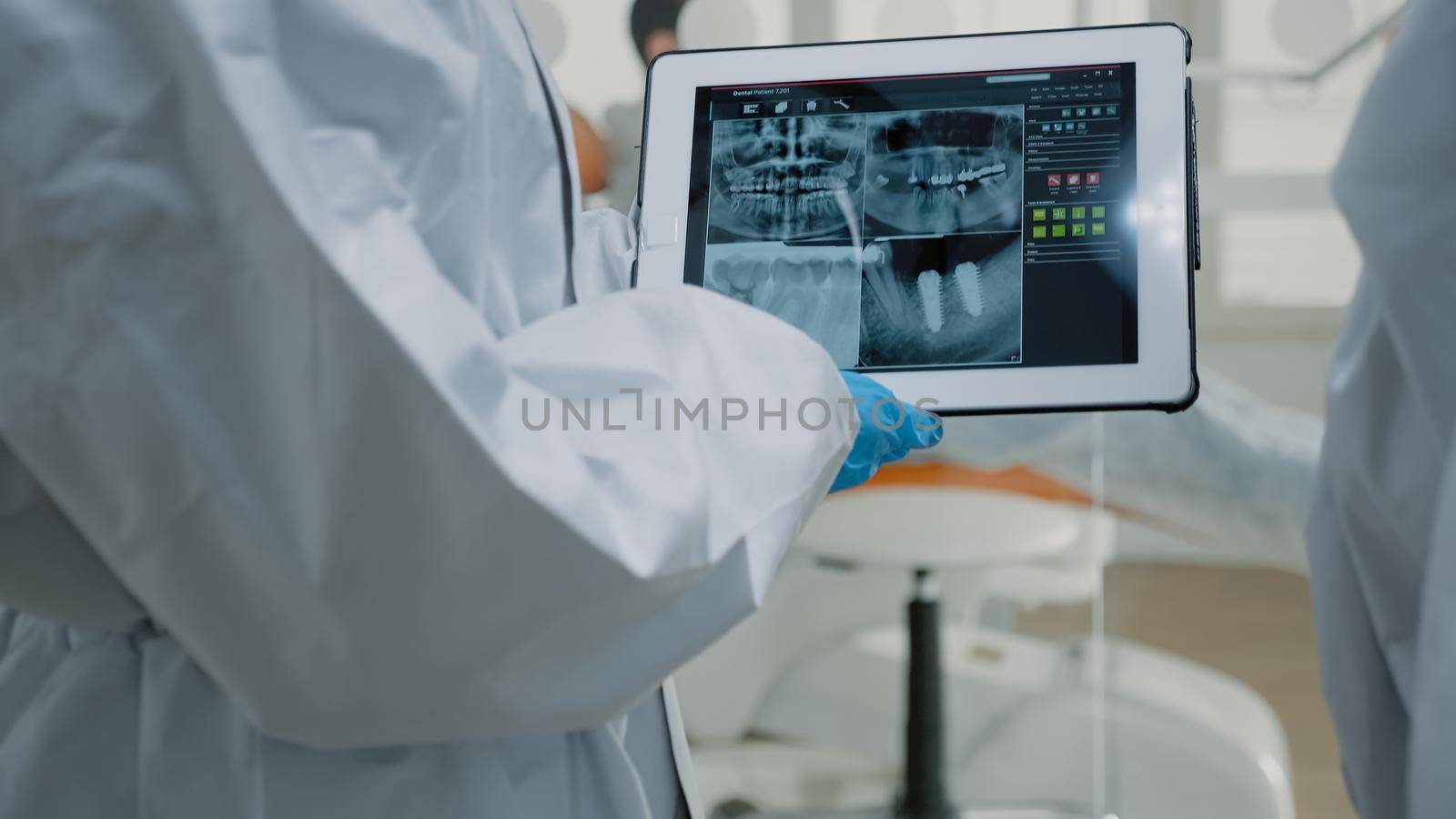 Close up of dental x ray on digital tablet screen in hand of orthodontists with ppe suits. Device with modern technology used for professional oral care protection and consultation