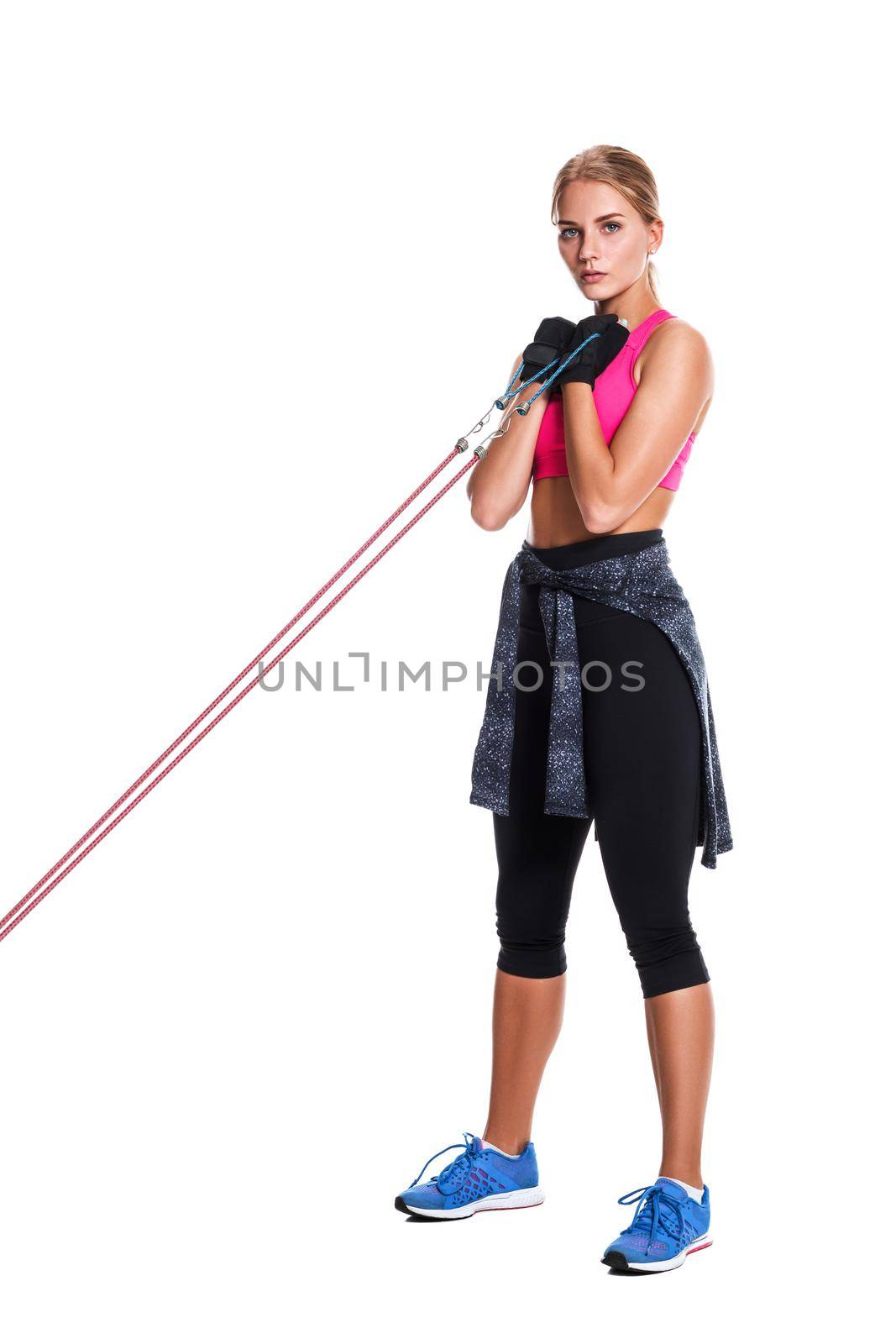 Strong woman using a resistance band in her exercise routine. Young woman performs fitness exercises on white background. Woman with beautiful slim healthy body posing in studio.