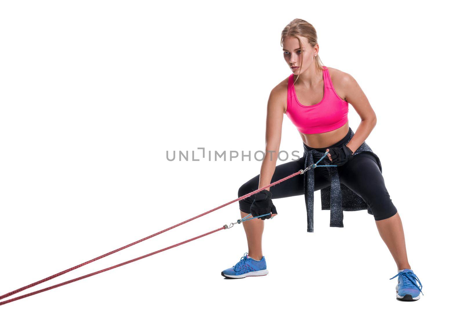 Strong woman using a resistance band in her exercise routine. Young woman performs fitness exercises on white background. Woman with beautiful slim healthy body posing in studio.