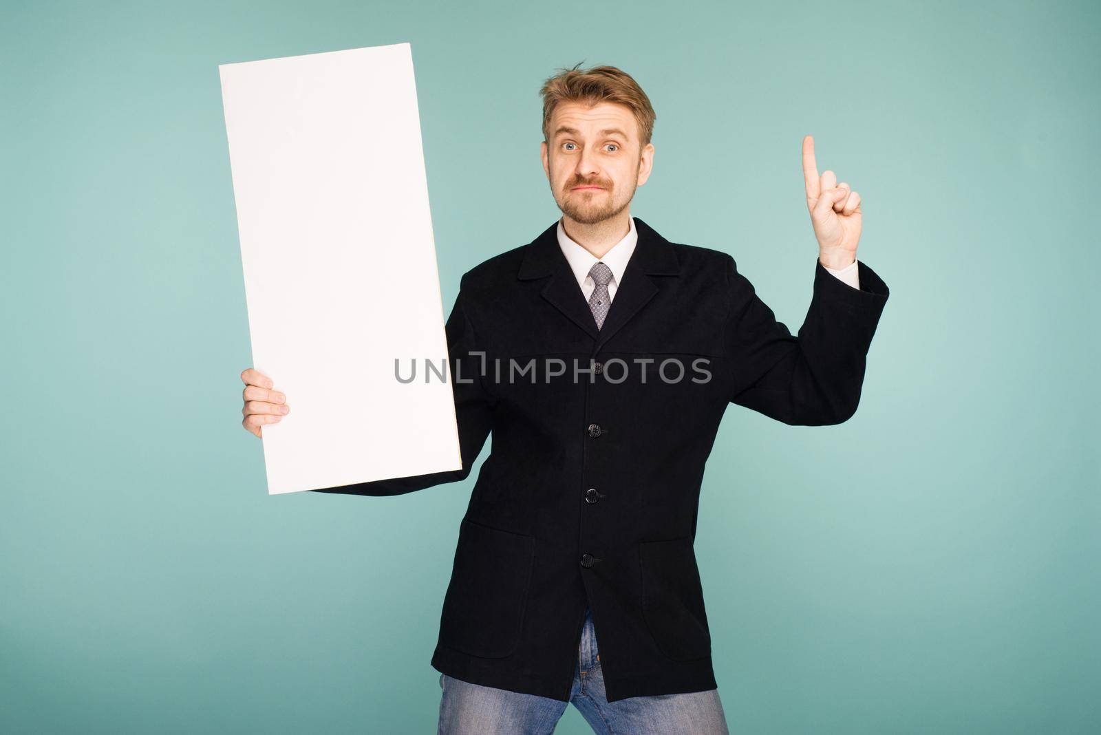 Happy smiling young business man showing blank signboard, on blue background