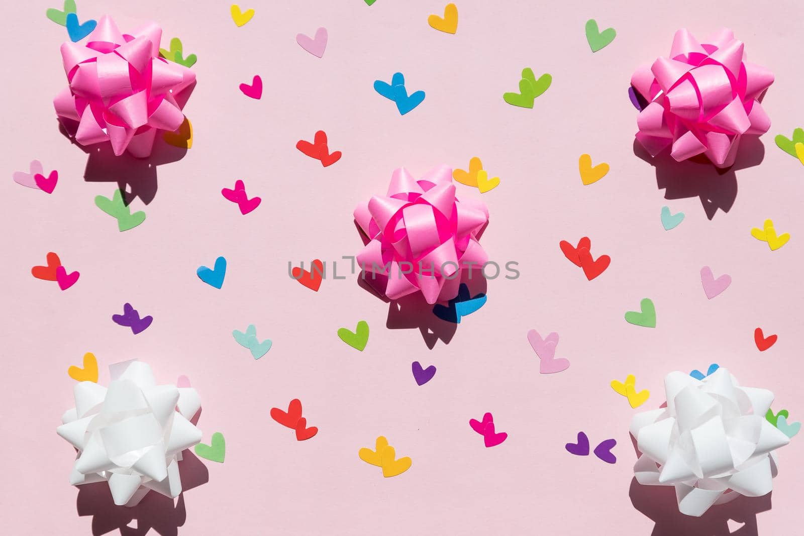 Beautiful silk hearts, white and pink holiday bows on a pink background. Celebrate concept.