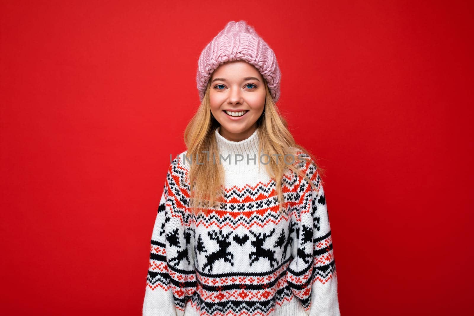 Attractive smiling happy young blonde woman standing isolated over colorful background wall wearing everyday stylish outfit showing facial emotions looking at camera by TRMK