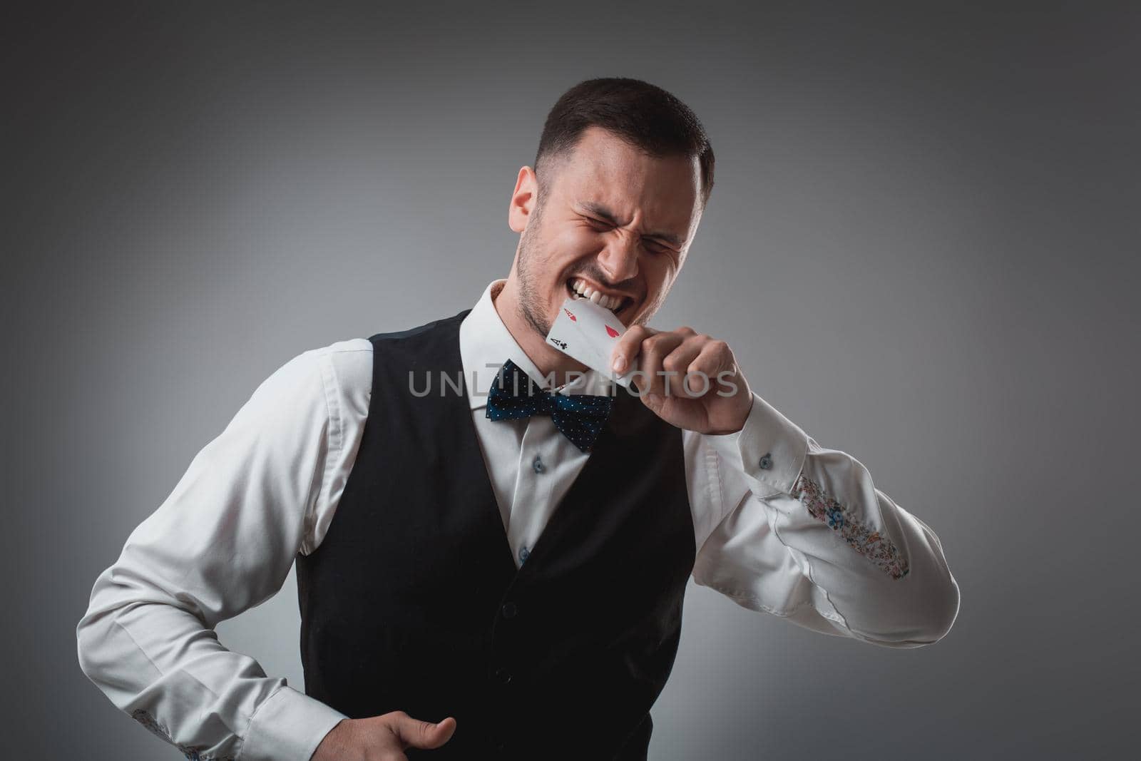 Handsome poker player with two aces in his hands. A man in the studio on a black-and-gray background