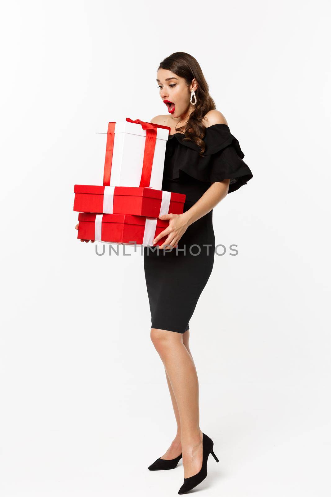 Merry christmas and new year holidays concept. Full length of attractive woman looking amazed at xmas gifts, receive presents, standing astonished over white background.