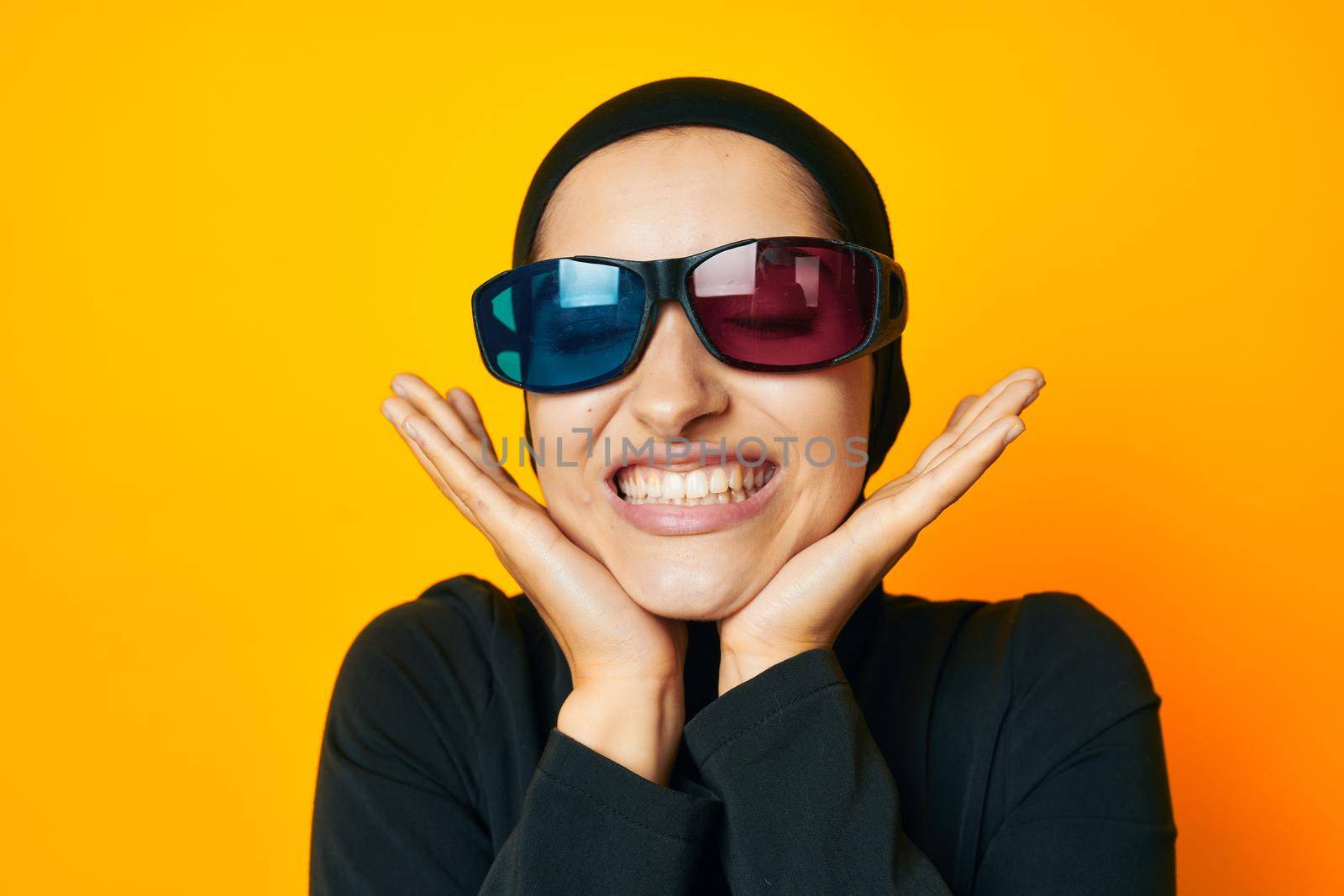 cheerful woman in black hijab popcorn 3D glasses cinema yellow background. High quality photo