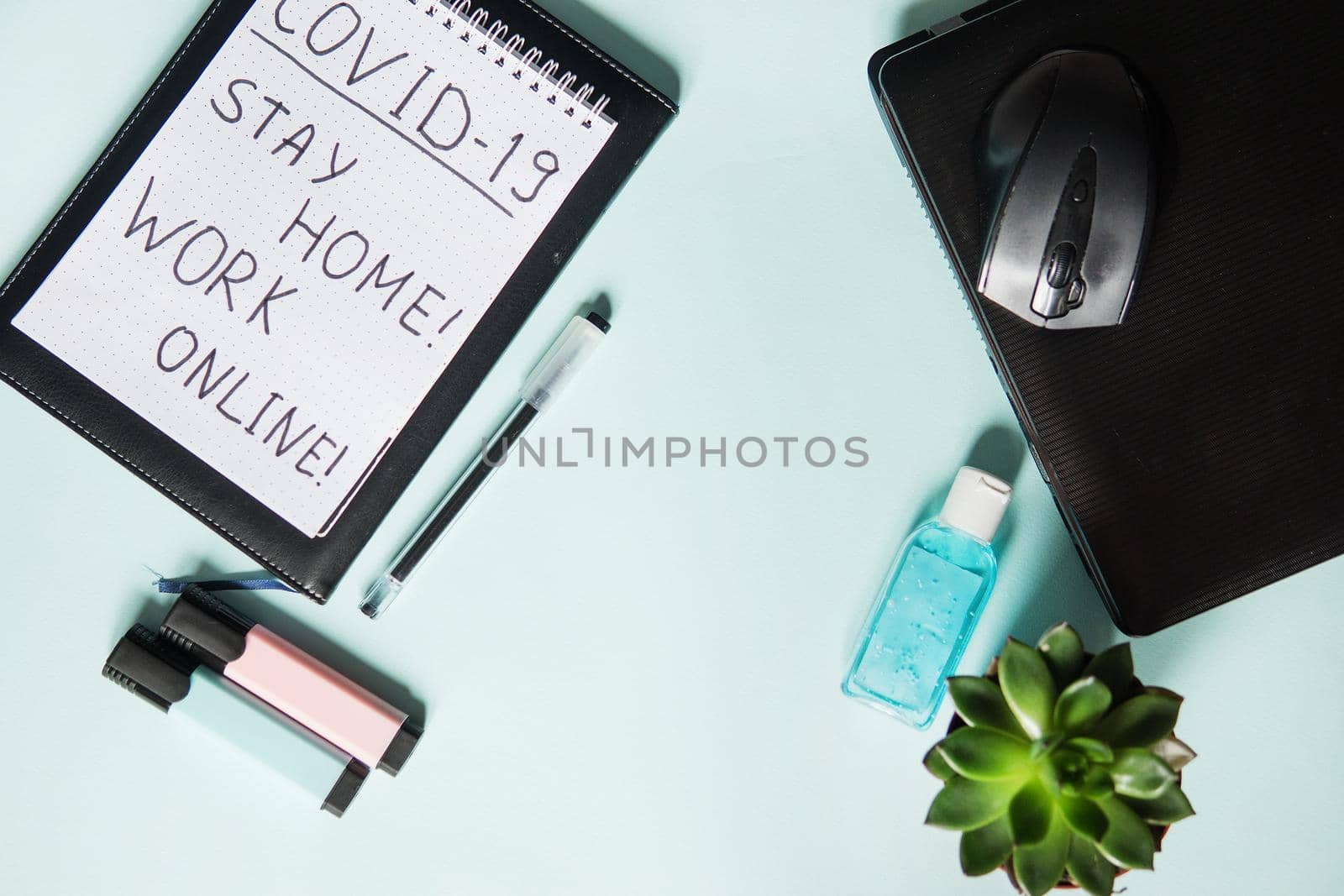 Top view of a desktop with notebooks, a markers, and a laptop. Text Covid-19, stay at home, WORK ONLINE. Work from home, protection from coronavirus during the quarantine period. Mint background.