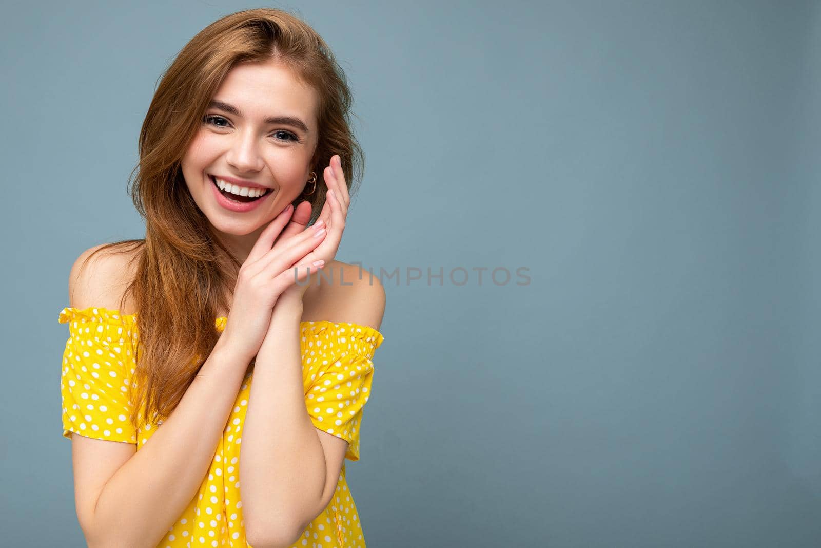Laughing smiling young beautiful dark blonde woman with sincere emotions isolated on background wall with copy space wearing stylish summer yellow dress. Positive concept.