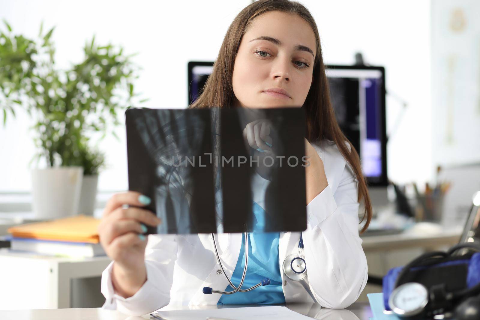 Doctor carefully examining xray of patient hand in clinic by kuprevich