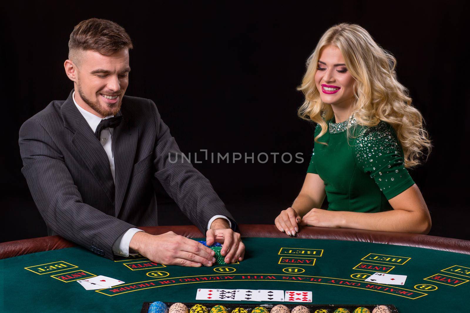 couple playing poker at the green table. The blonde girl and a guy in a suit. happy win