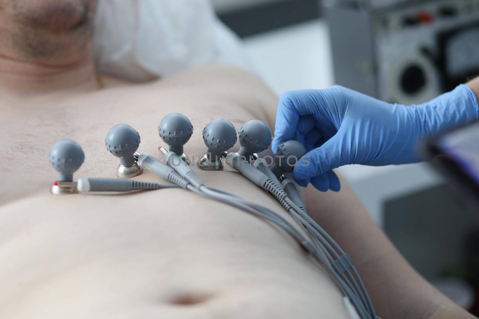 Nurse attaching suction cups to patient chest to record electrocardiogram closeup by kuprevich