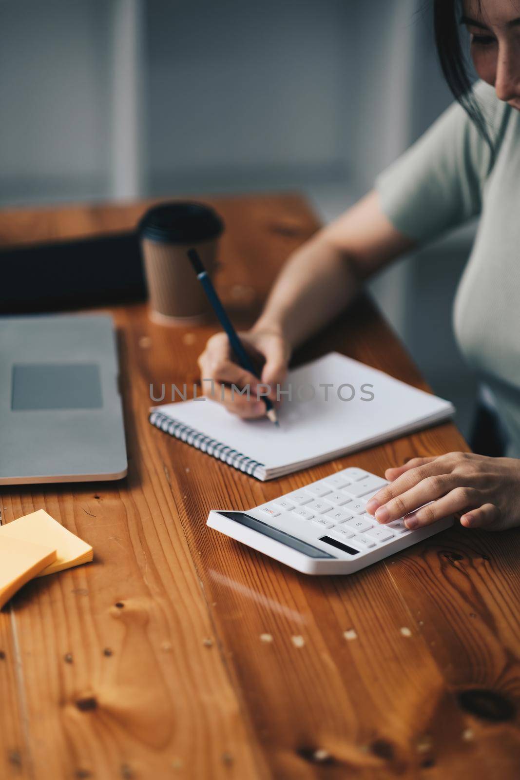 close-up shot of accountant using calculator while taking notes on office desk