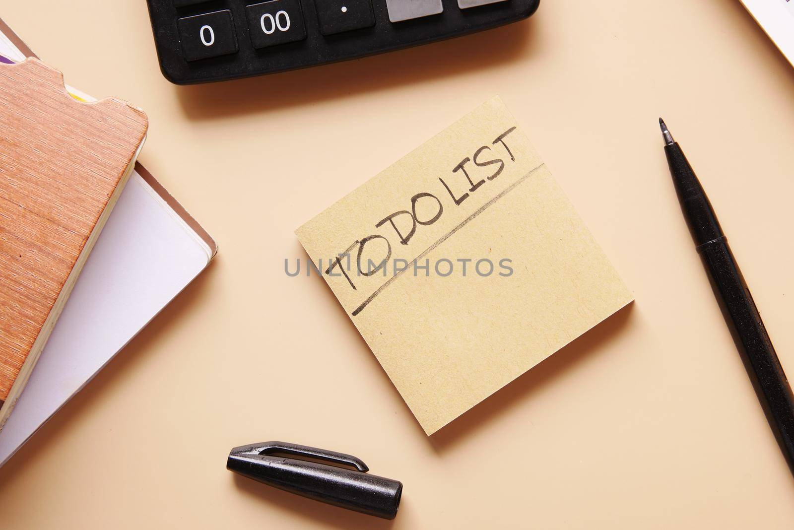 To do list in notebook with office suppliers on desk
