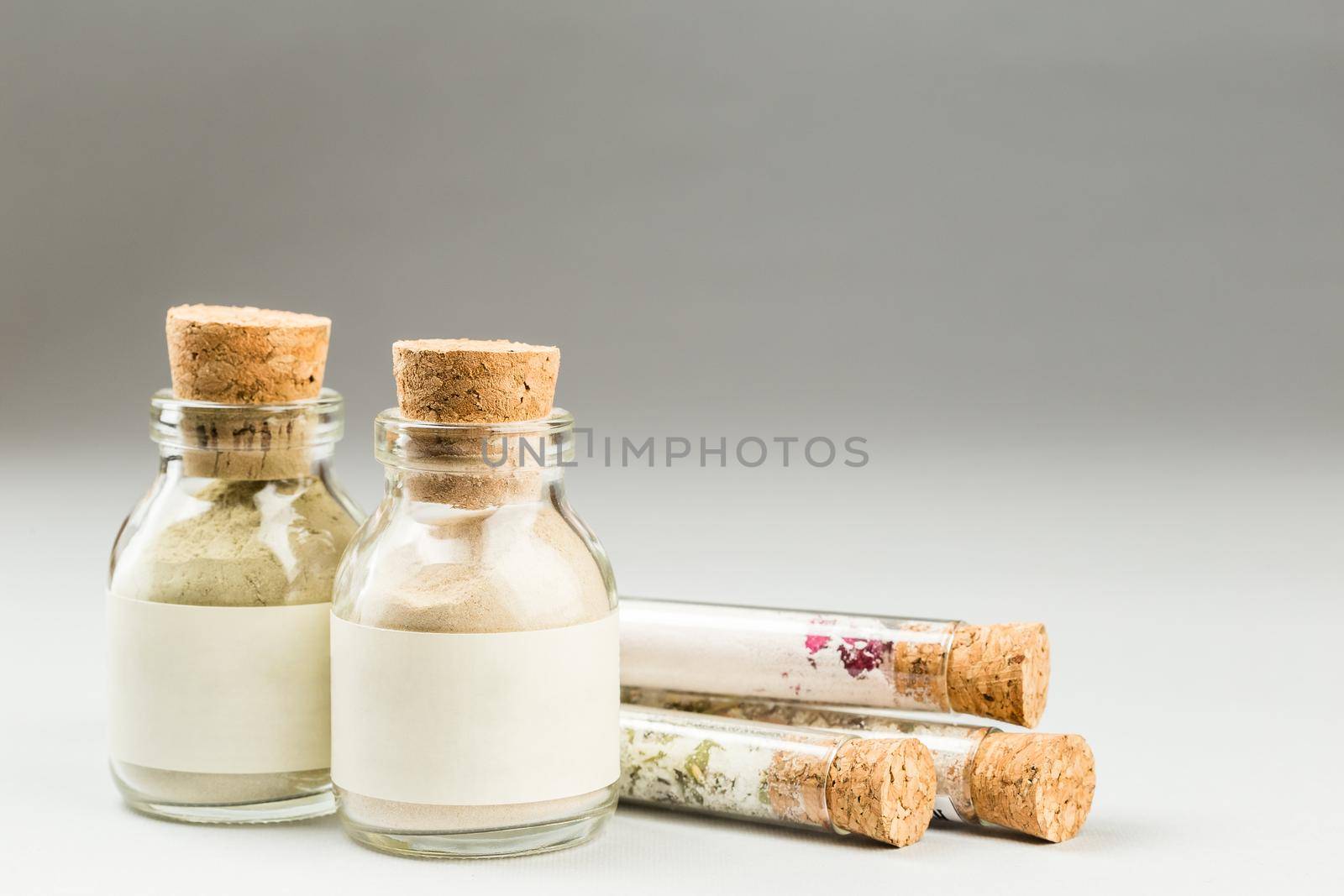 Ubtan face mask powder and bath salts in glass tubes, on grey background. SPA natural cosmetics set.