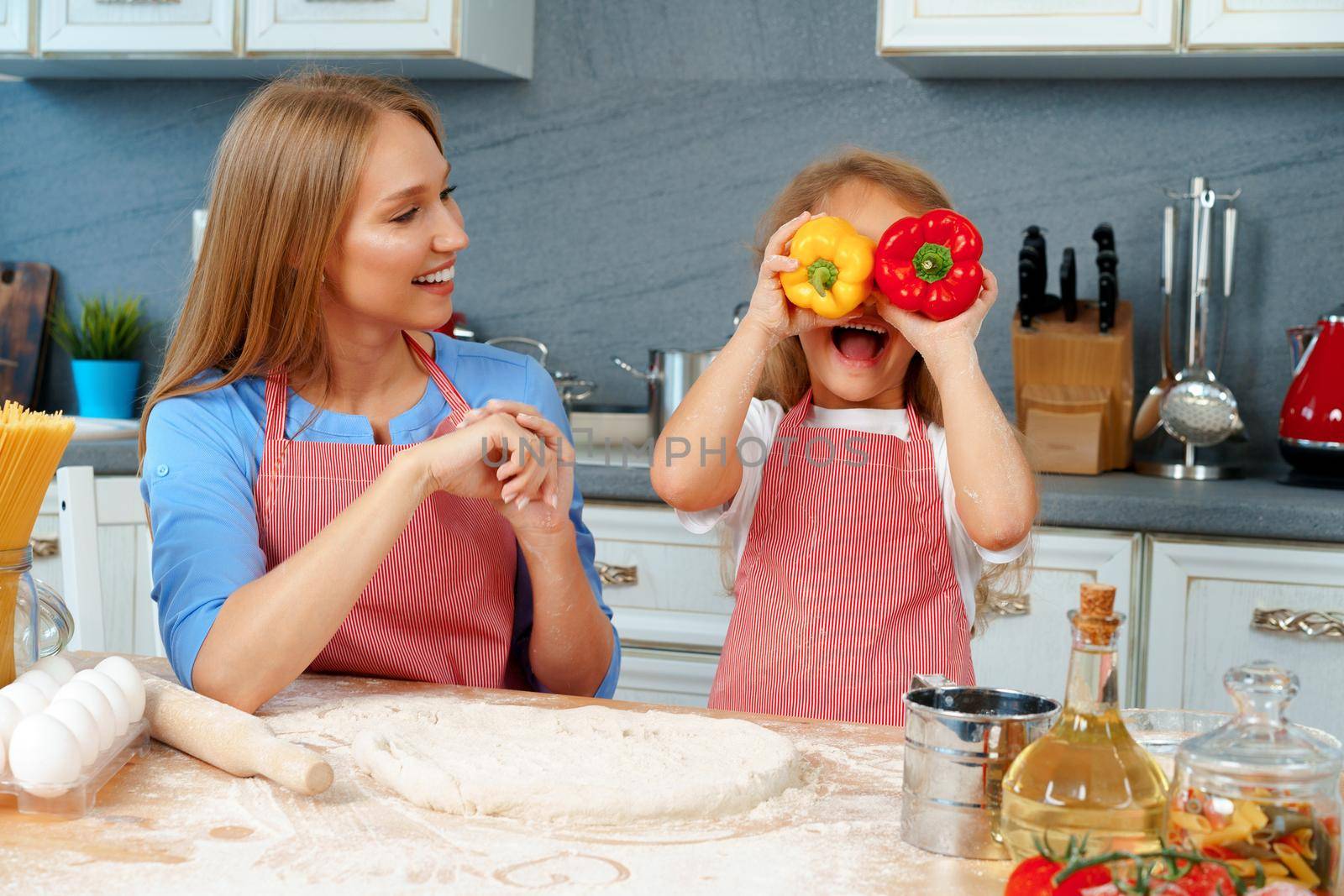 Beautiful mother and her adorable daughter having fun in the kitchen while cooking food at home