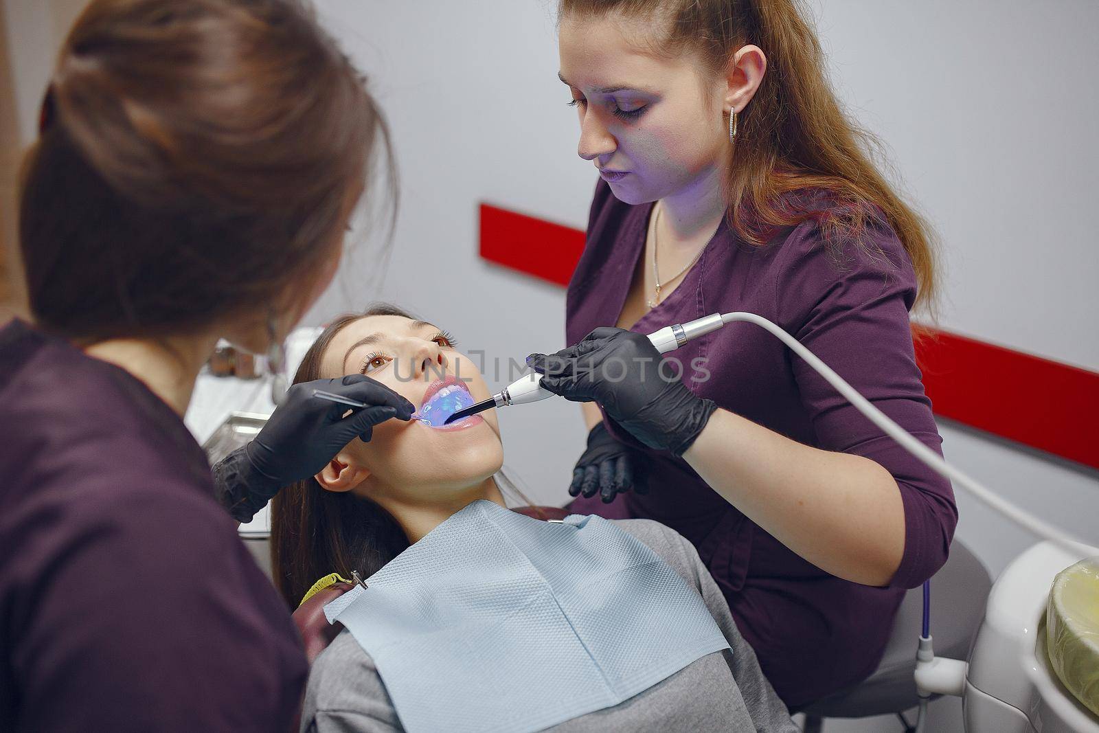 Beautiful lady in the dentist's office. Woman in a purple uniform