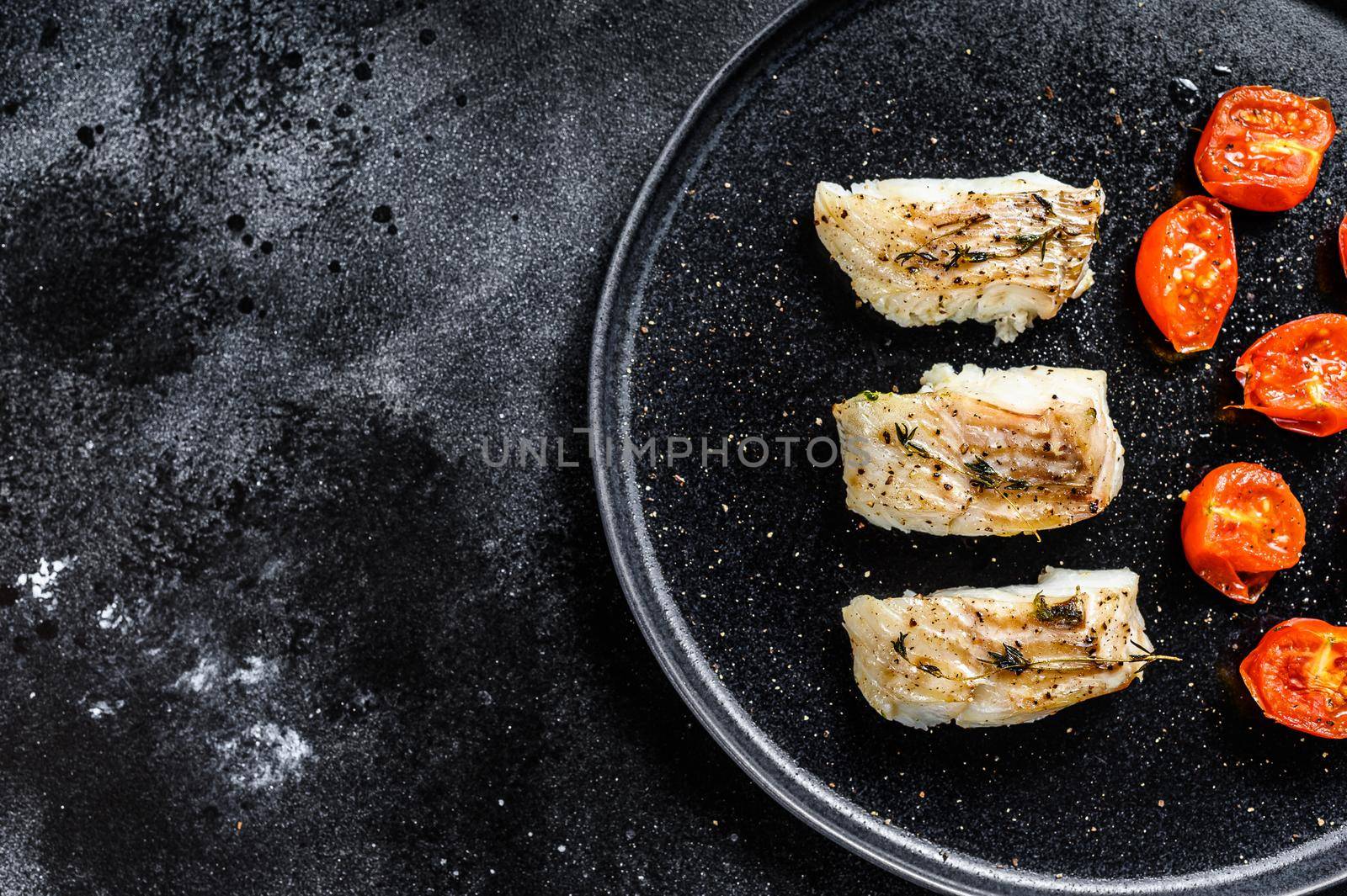 Baked cod fish fillet with spice. Black background. Top view. Copy space by Composter