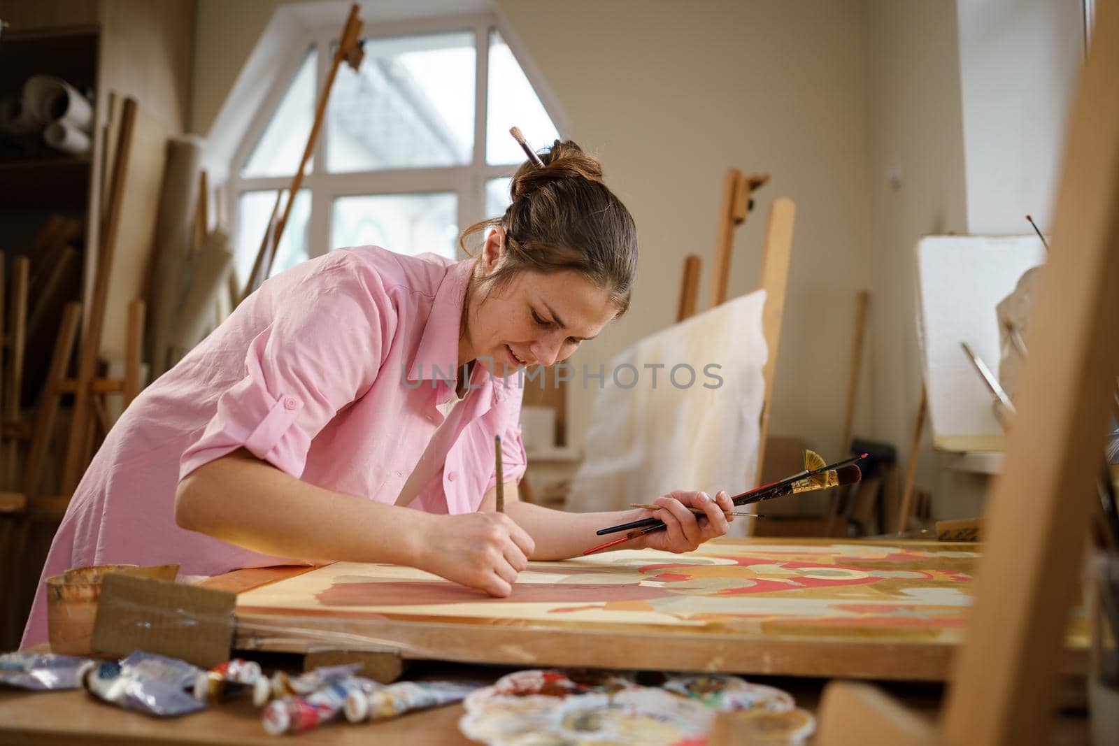 Art, creativity, hobby and creative occupation concept. Bringing creativity to life. Woman painting in art studio. Attractive female artist painting in workshop. Woman hobby, activity, profession by Tomashevska