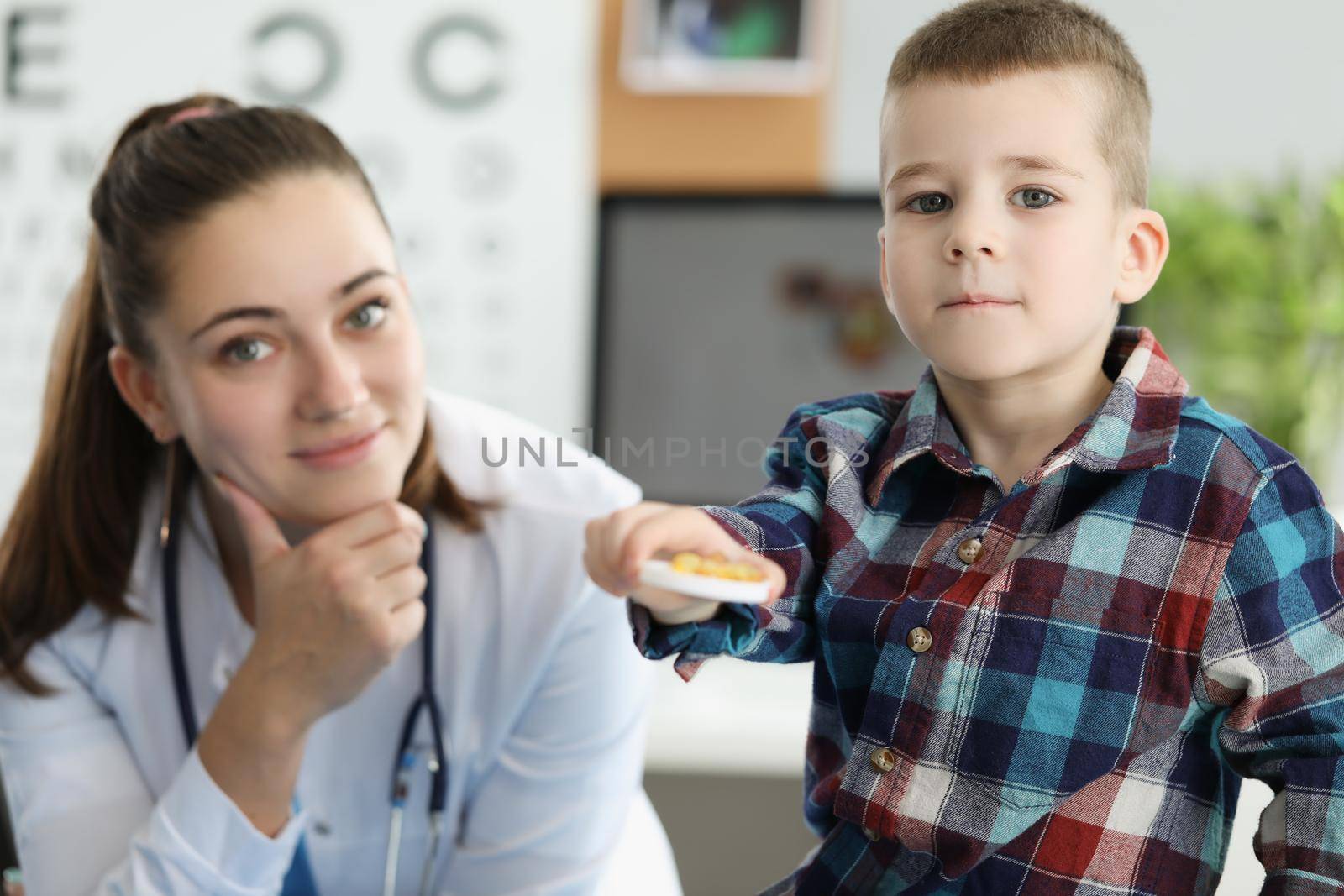 Little boy holding yellow gelatin capsules at doctor appointment. Taking vitamin D and preventing rickets in children concept