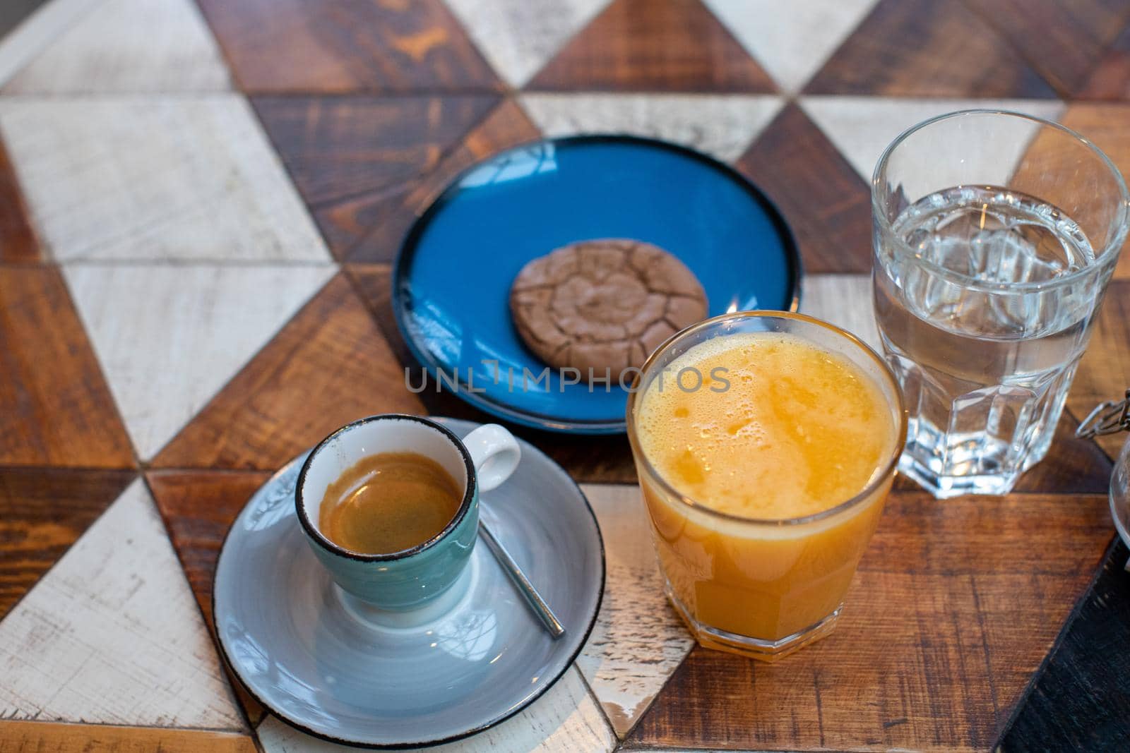 From above of table with cup of espresso cookie on plate and fresh orange juice