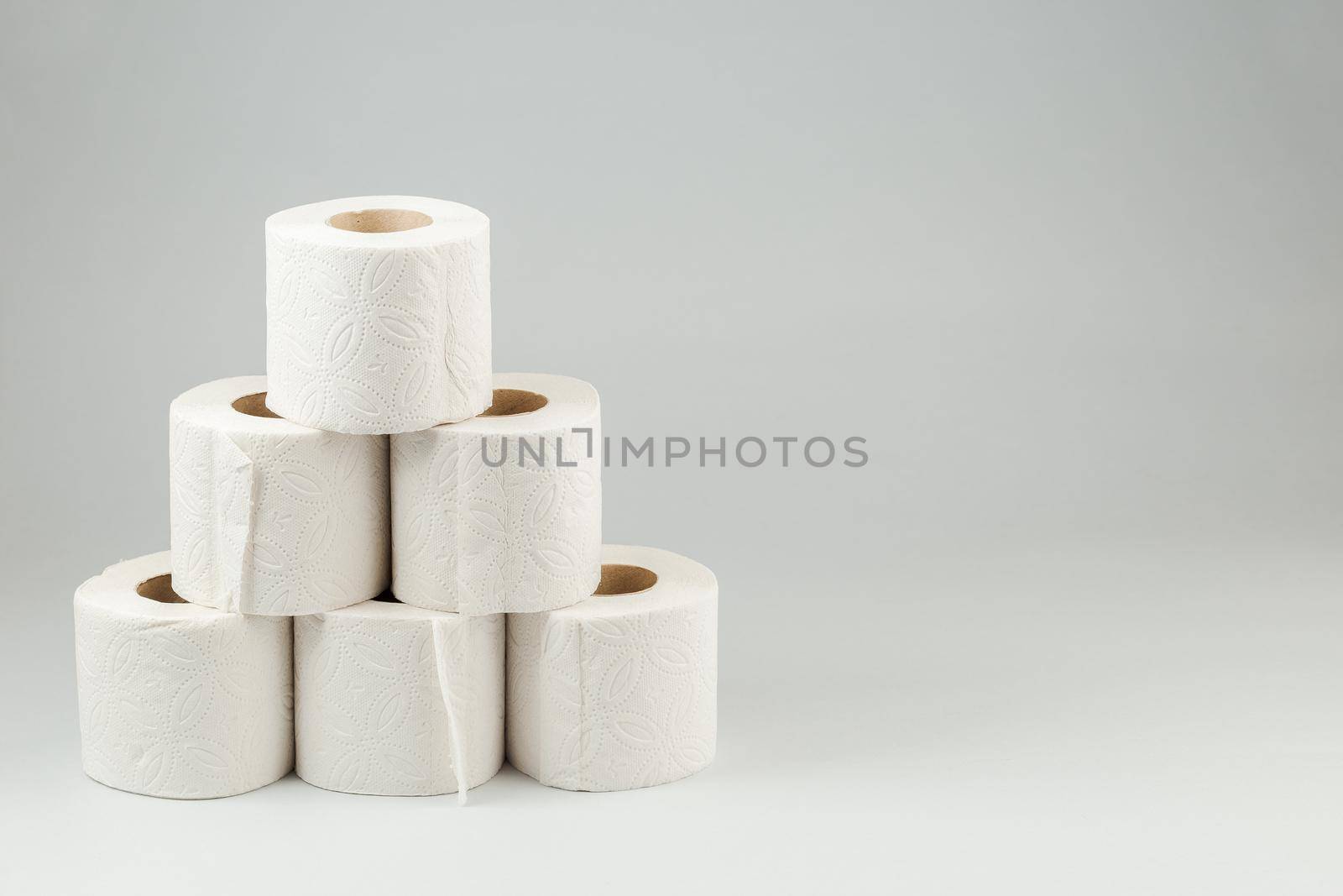 A Pyramid of Toilet Paper Rolls over Gray Background. Copy Space for text