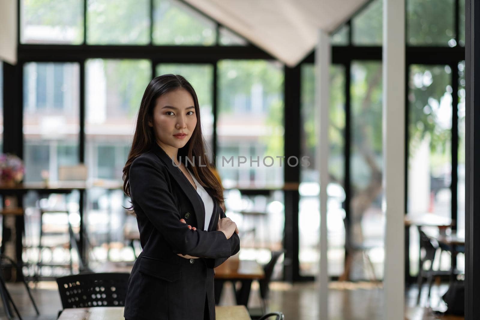 Portrait of successful young Asian businesswoman at office, She standing and looking at camera wears a black suit