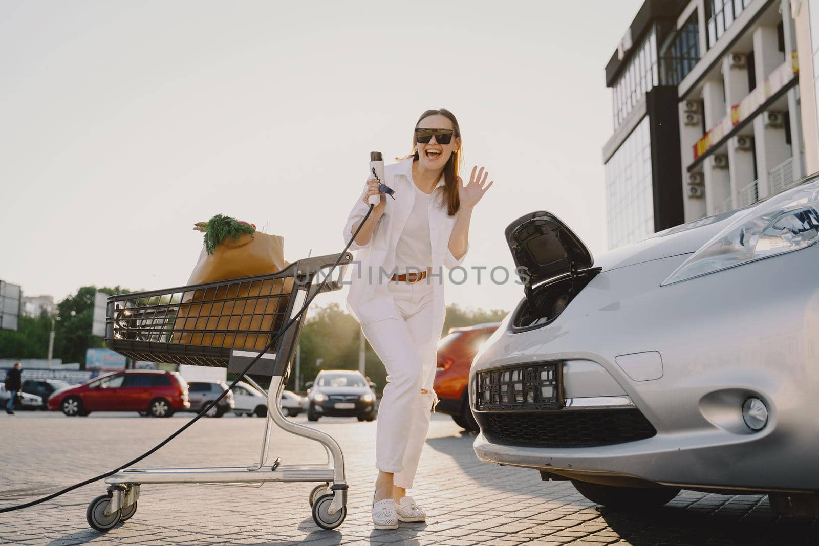 Woman charging electro car at the electric gas station by prostooleh