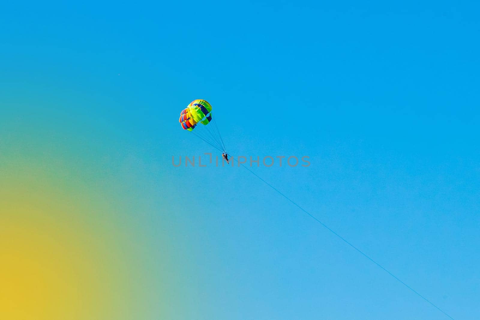 A man and a woman tourists are parachuting against the blue sky. Extreme vacation concept by AYDO8