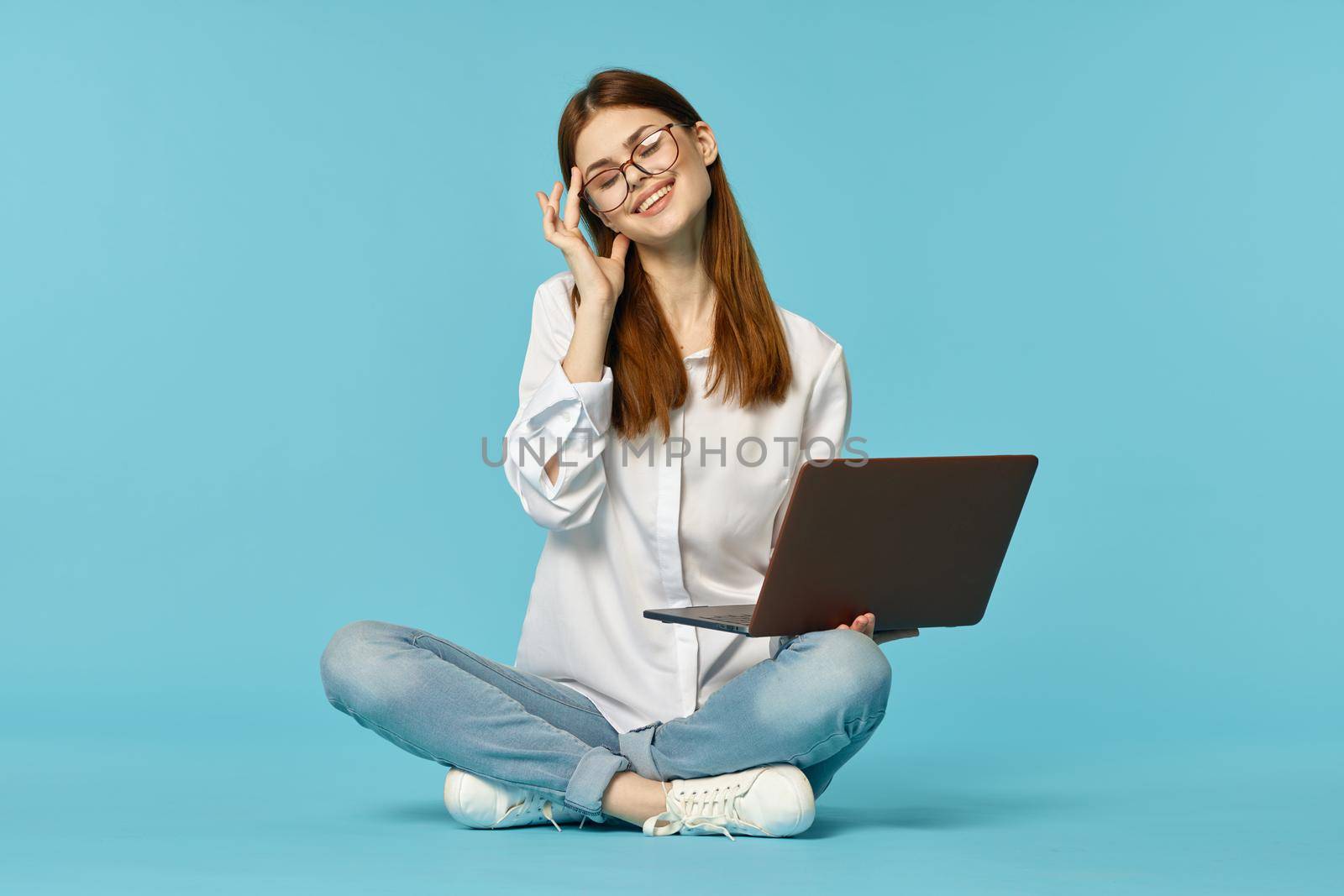 woman student sitting on floor with laptop education blue background. High quality photo