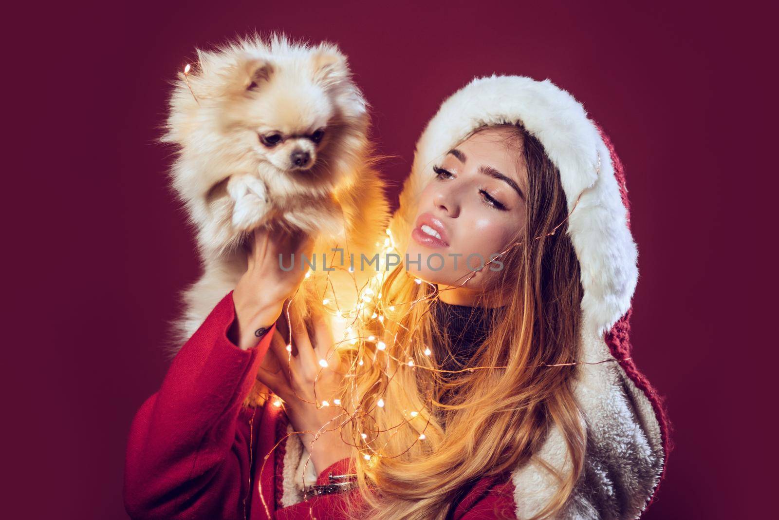 Woman with pomeranian spitz dog at xmas. Girl in santa costume with pet. Christmas and winter holiday. New year of dog by Tverdokhlib