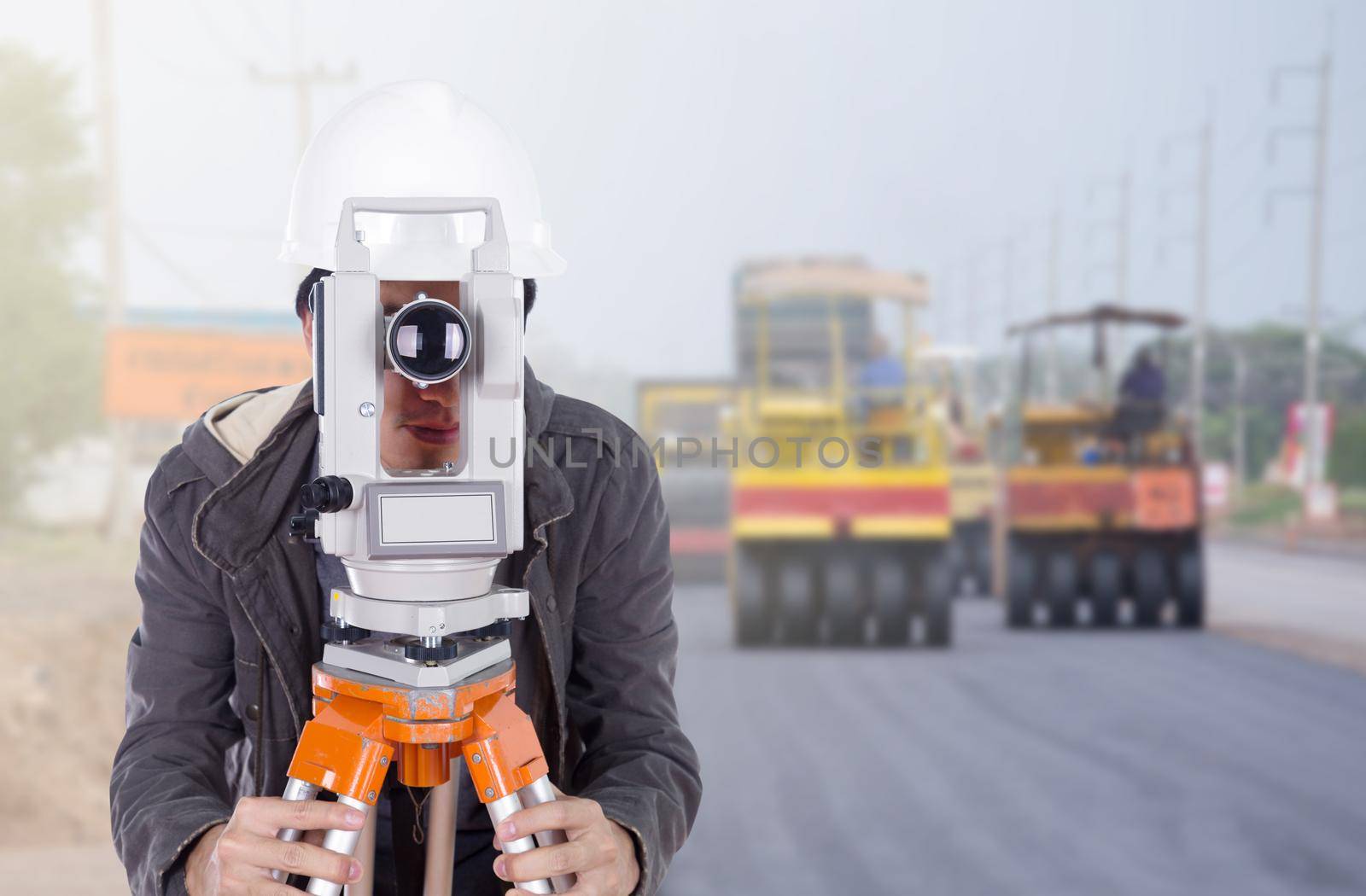 engineer working with survey equipment theodolite with road under construction background