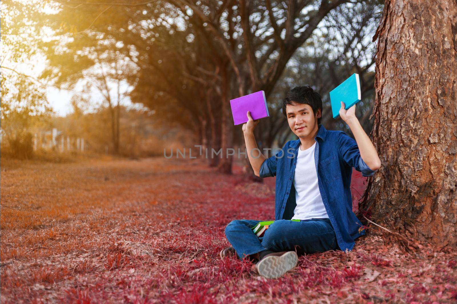 young man sitting and holding a book in the park