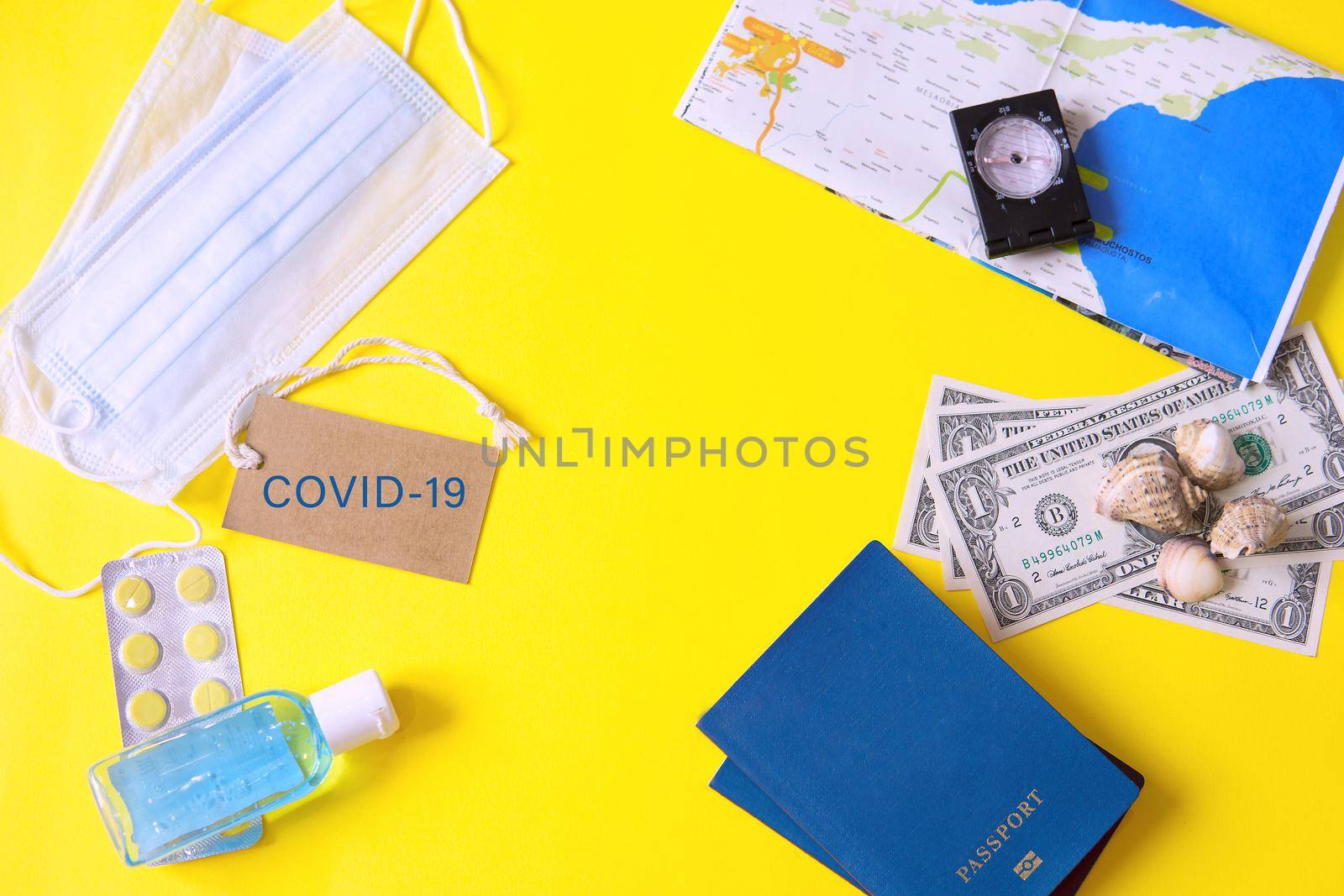 Travel concept with tablets, sterile mask, antiseptic and road symbols id passport, money, compass, map on yellow background. Stop traveling to dangerous places to prevent coronavirus. Space for text