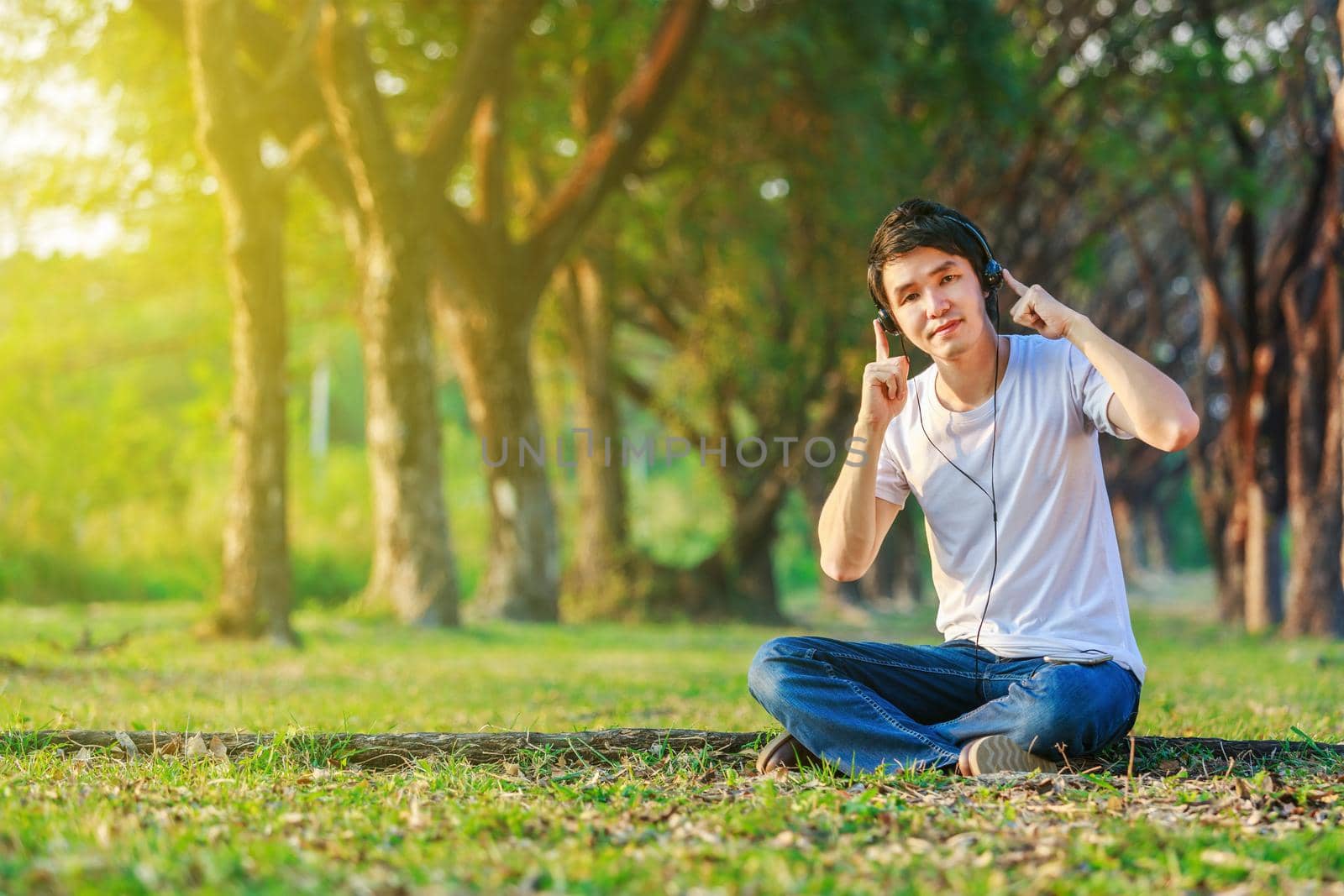 young man listening to music with headphones from mobile in the park