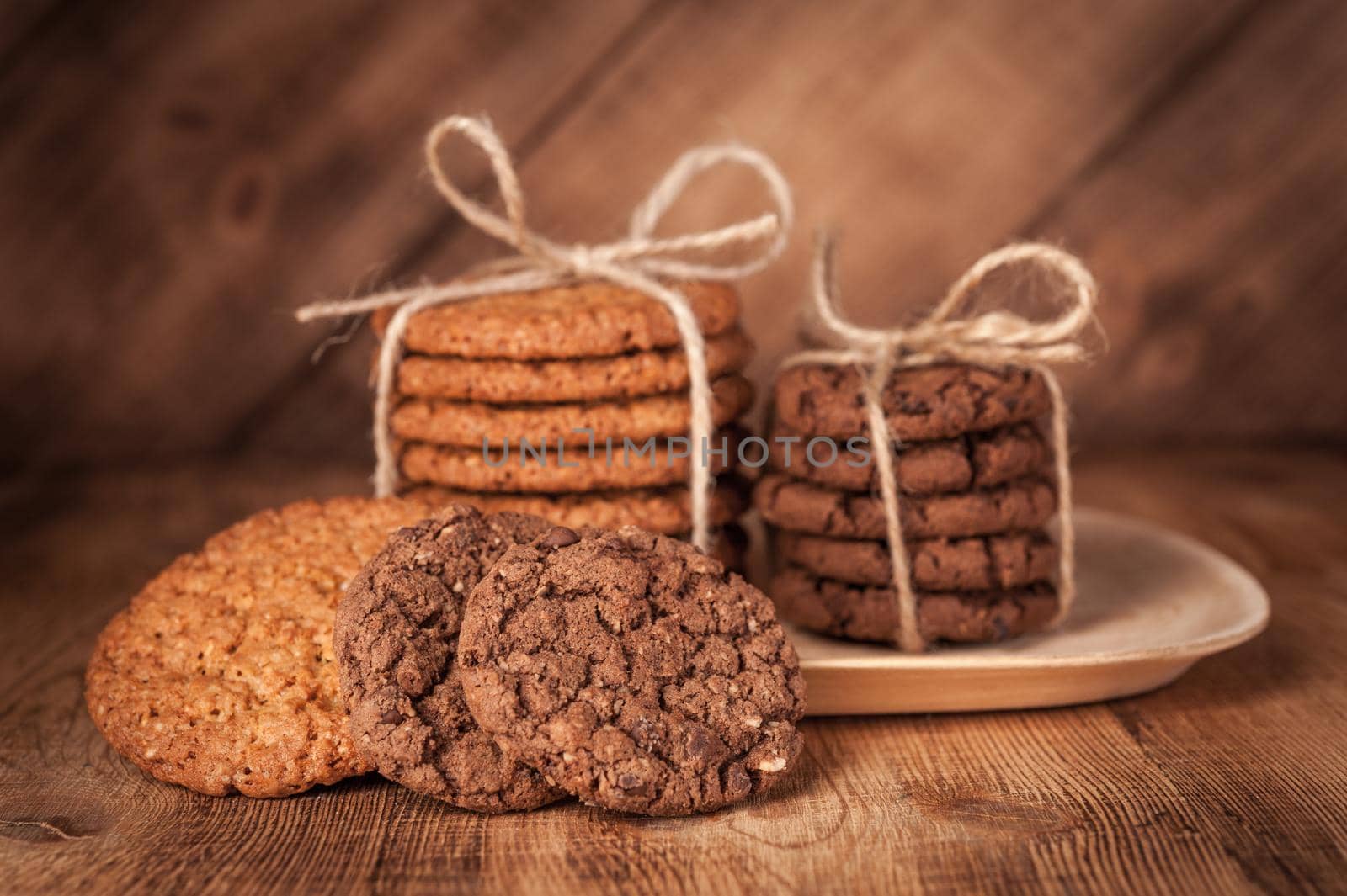Homemade corded wholegrain cookies with oatmeal, linen and sesame seeds and traditional cookies with chocolate chips on dark rustic wooden table. Healthy vegan food concept.