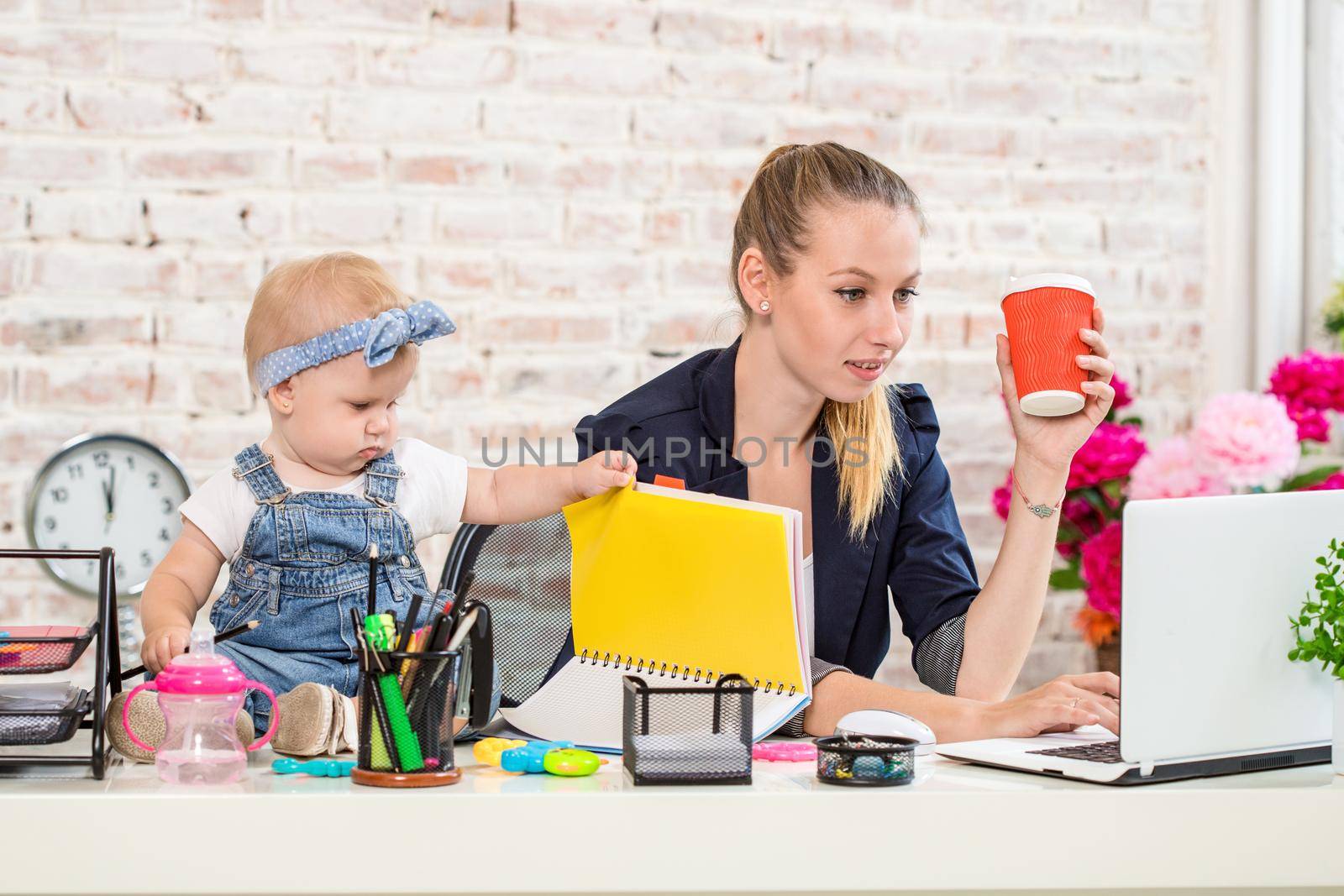 Businesswoman mother woman with a daughter working at the laptop. At the workplace, together with a small child