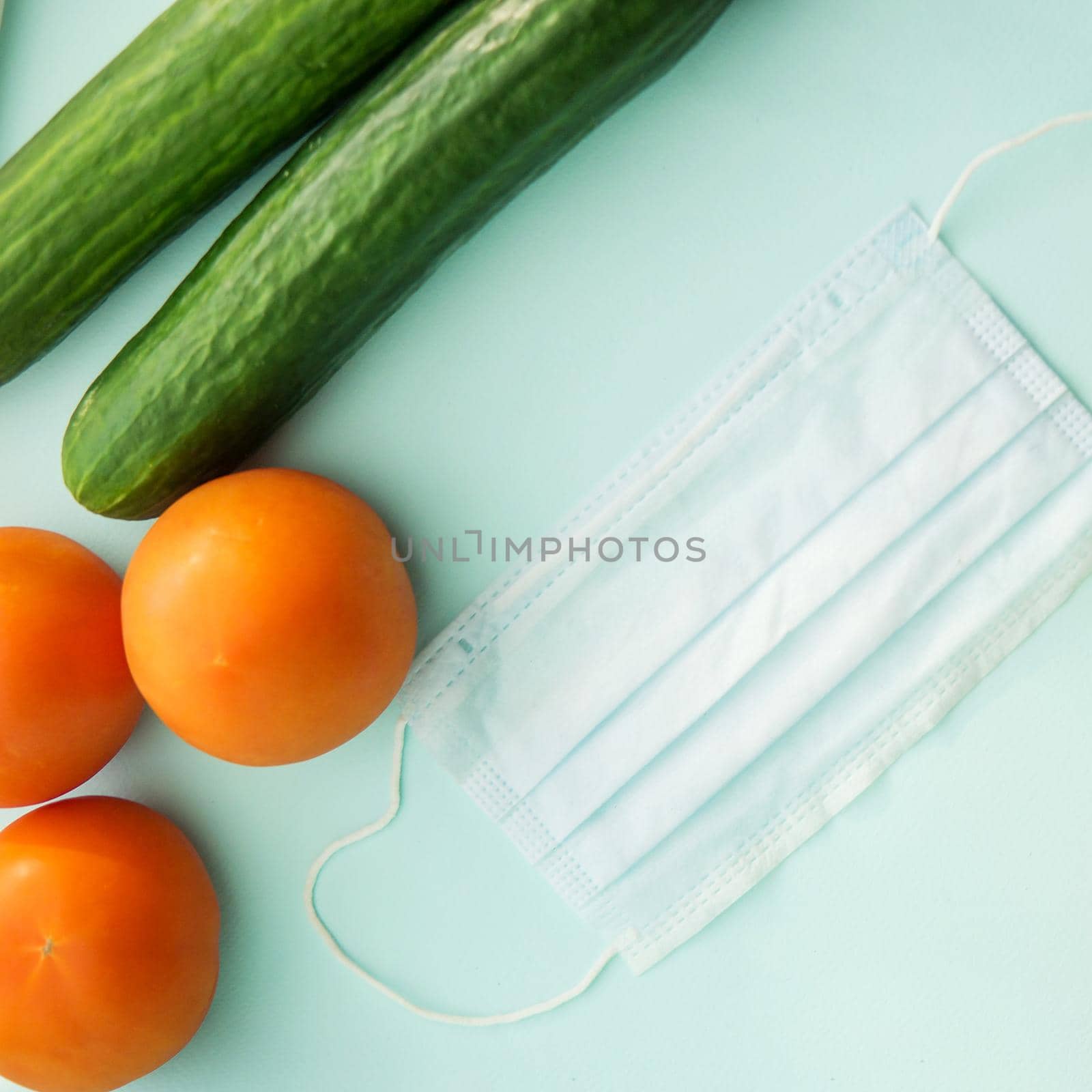 Vegetables and protective mask on a mint background, vegetable harvest, protection from coronavirus, fruit from China. Close-up, top view, flat lay. Square image.