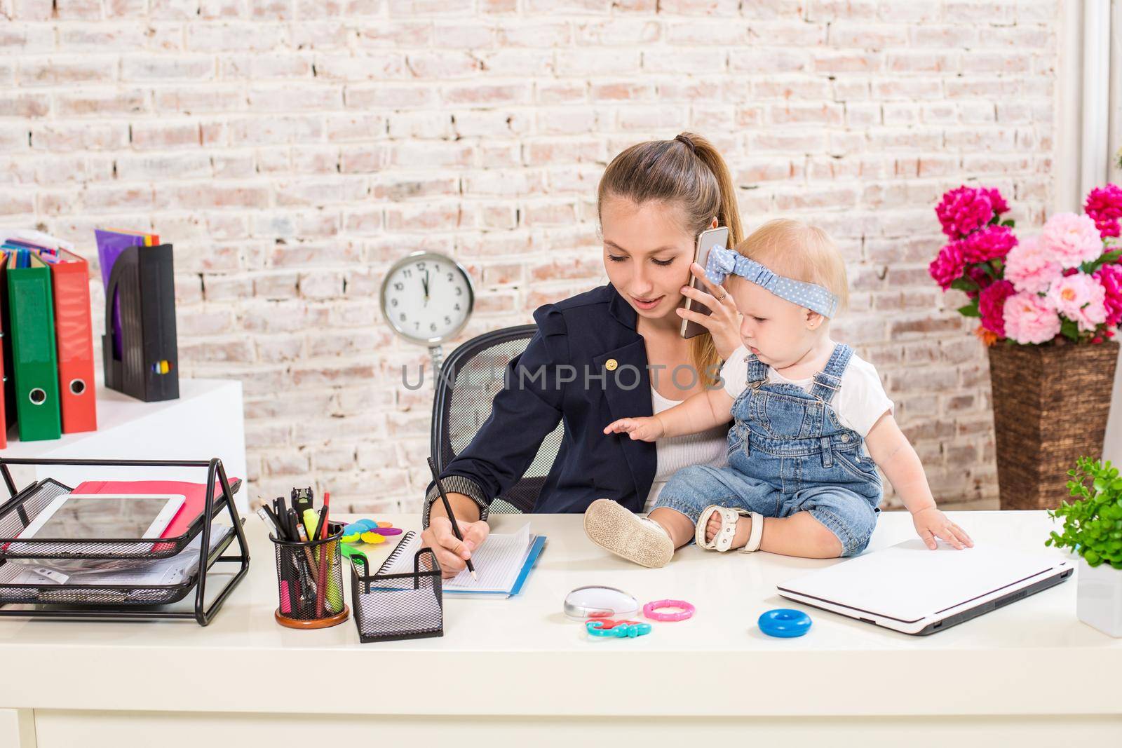 Mom and businesswoman working with laptop computer at home and playing with her baby girl. Horizontal shape, front view, waist up