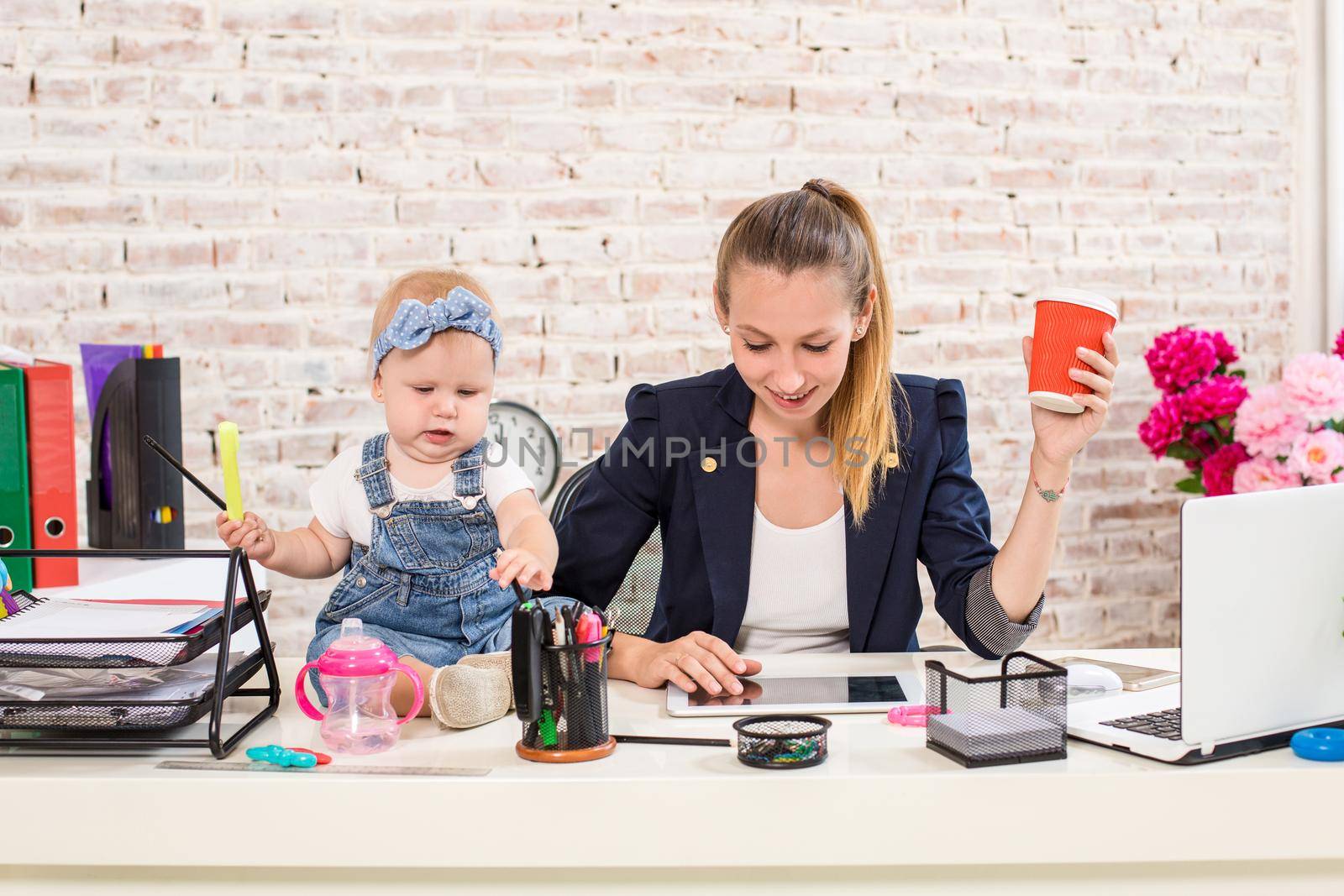 Mom and businesswoman working with laptop computer at home and playing with her baby girl. by nazarovsergey