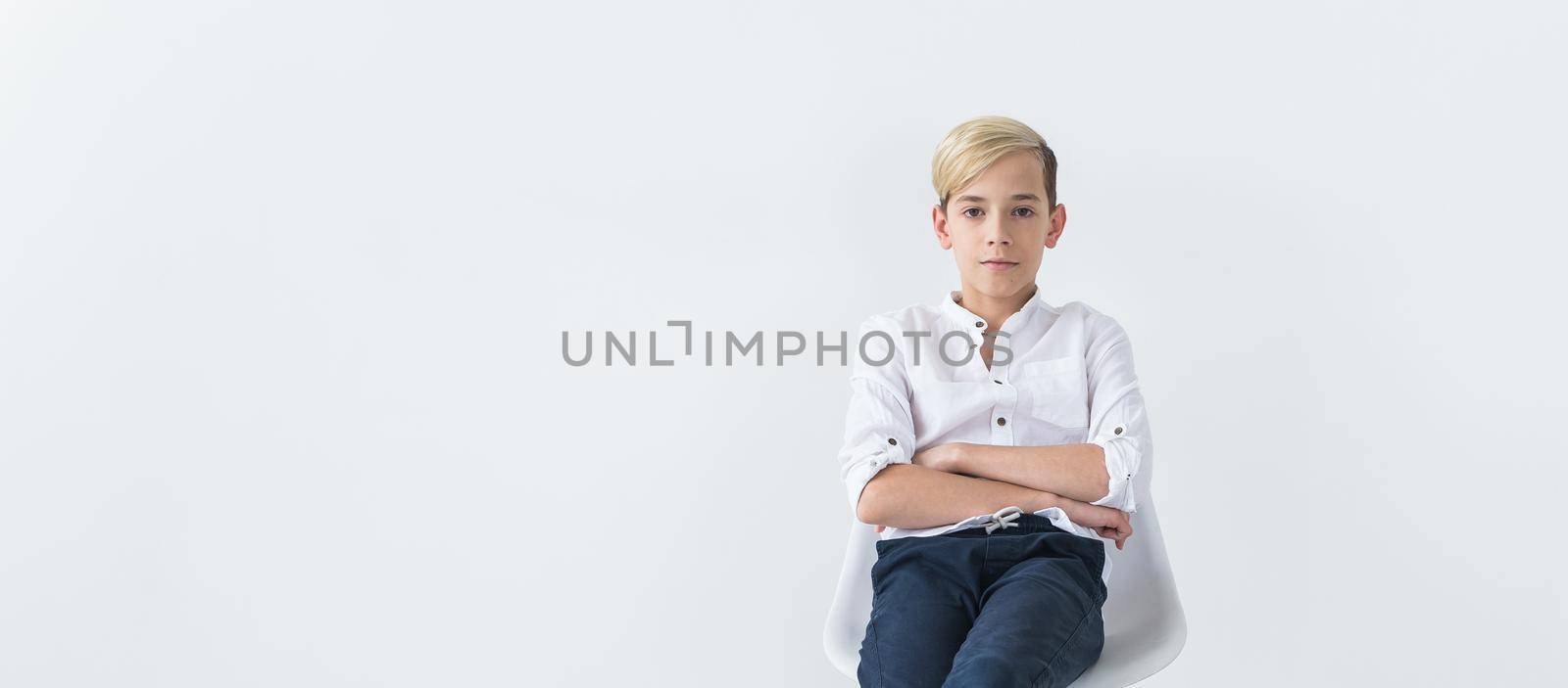 Solitude, loneliness and boredom concept - Bored teen student sitting in a school chair isolated on white background by Satura86