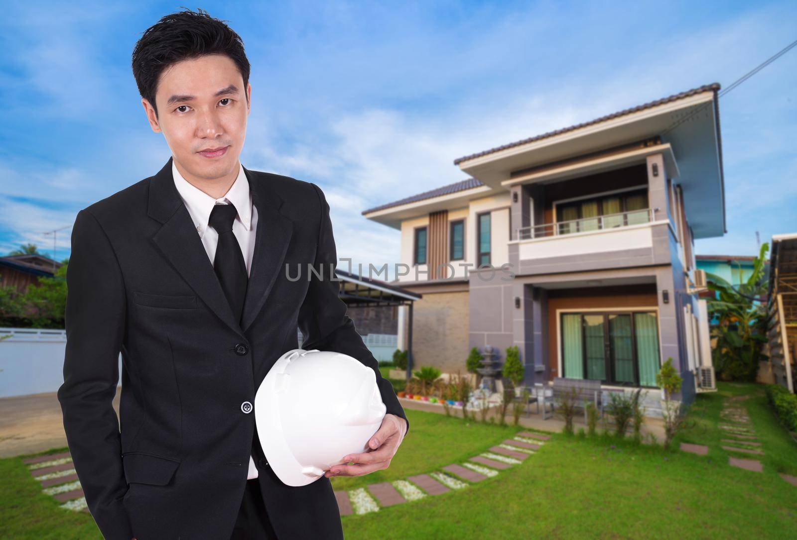 engineer holding helmet with modern house background