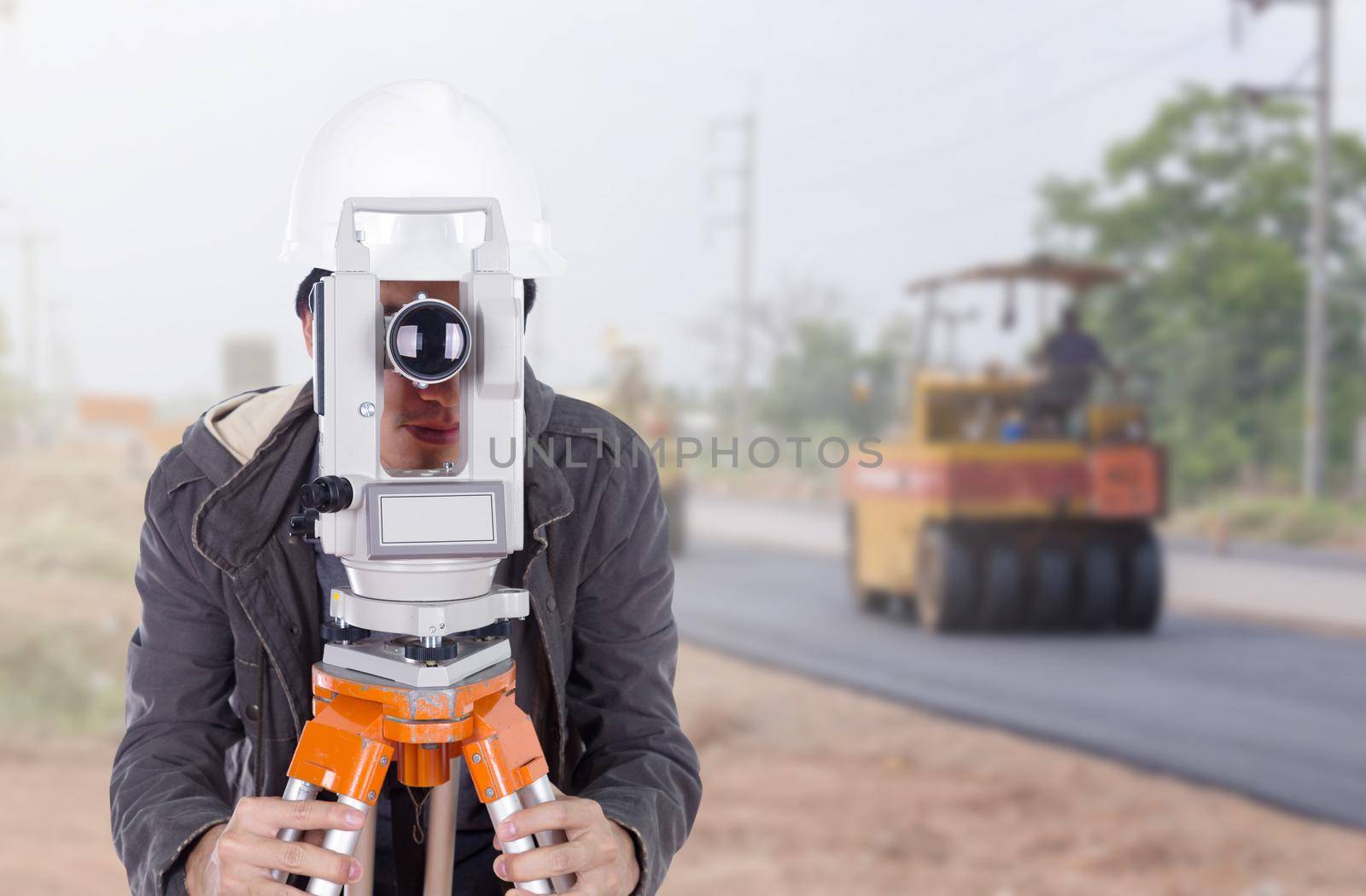 engineer working with survey equipment theodolite with road under construction background