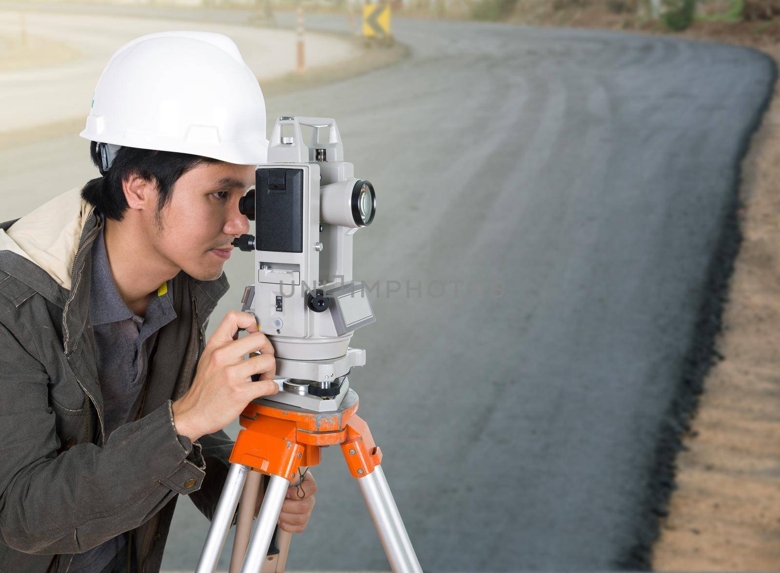 engineer working with survey equipment theodolite with road under construction background