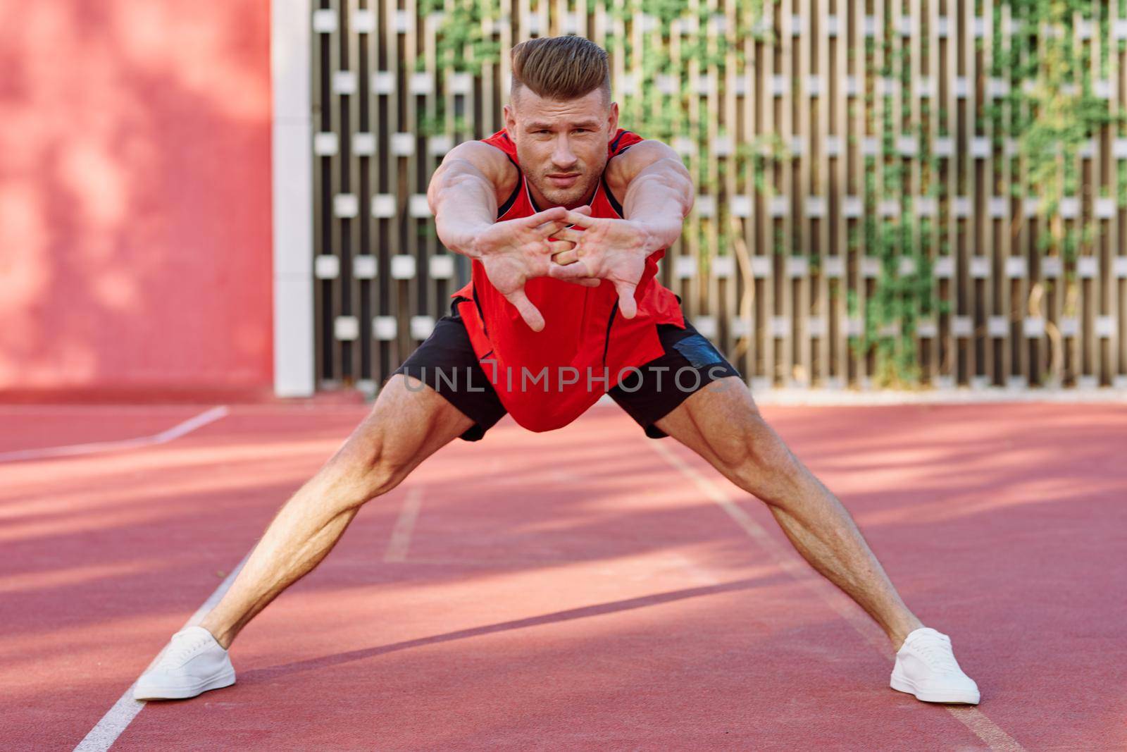 athletic man in red jersey on the sports ground exercise. High quality photo