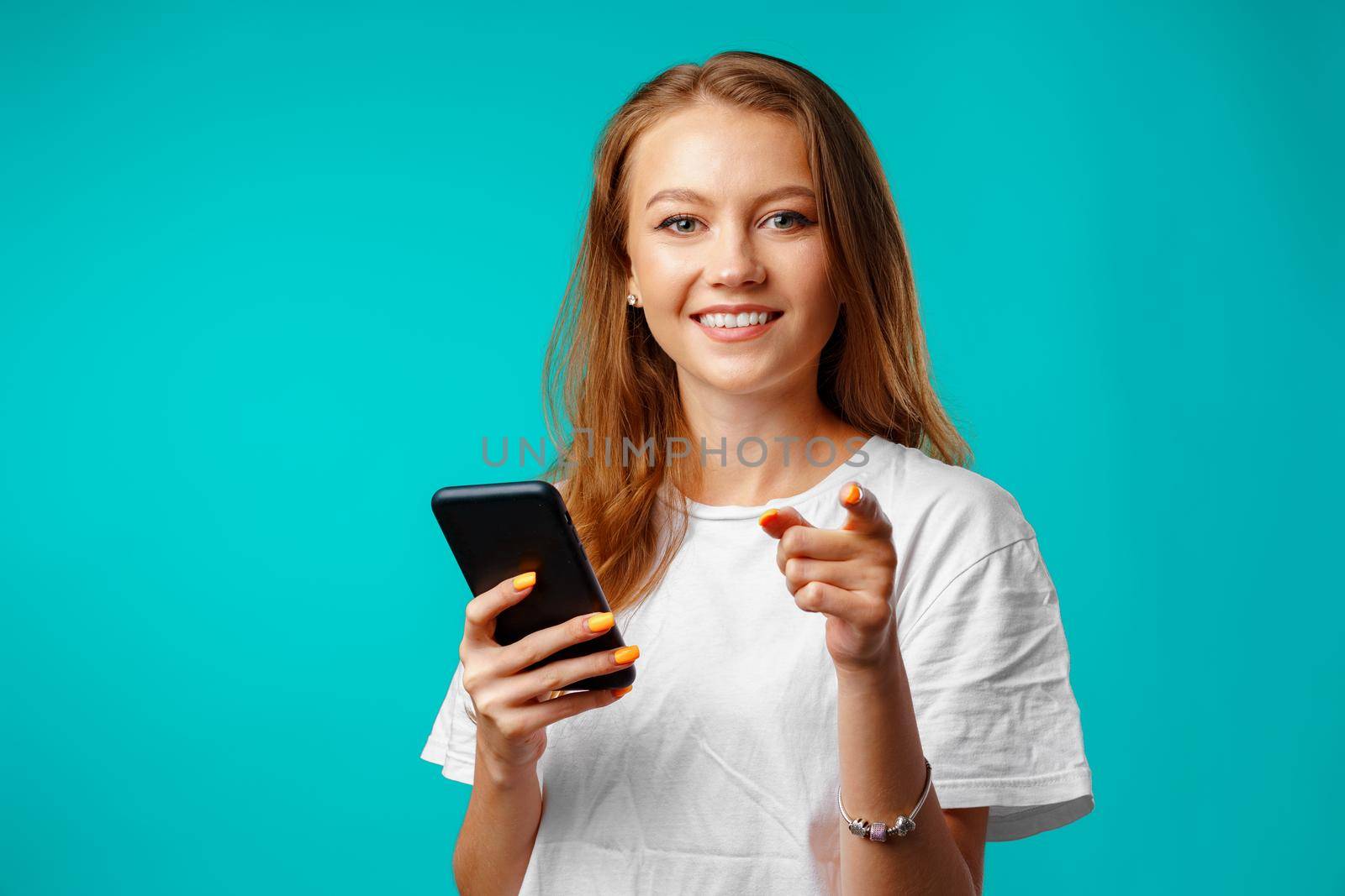 Young smiling woman standing and using her smartphone against blue background