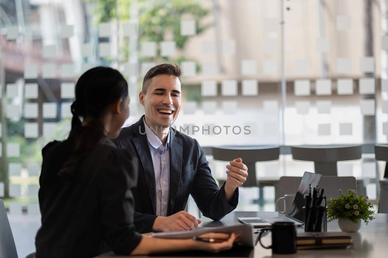 Asian and caucasian businesspeople learn new business app, apprentice listen associate tell about corporate program. Multiracial client and bank manager at business meeting using laptop negotiating.