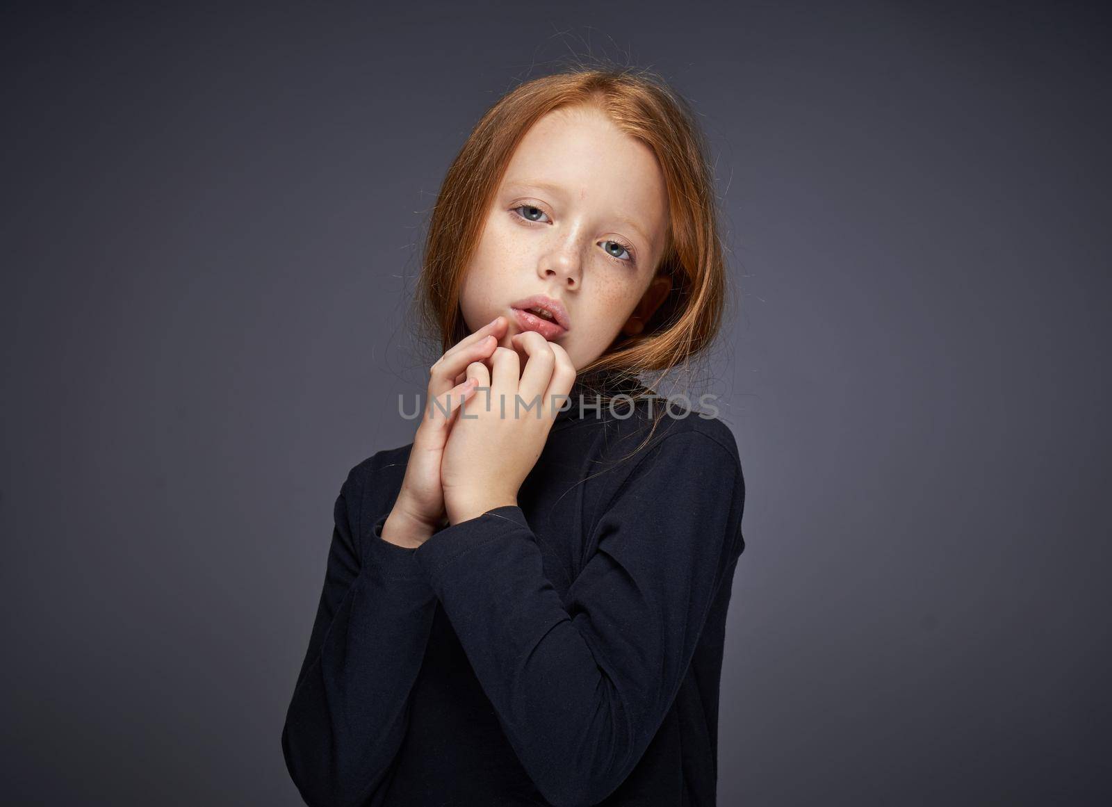 red-haired girl with freckles on her face in a black sweater posing. High quality photo