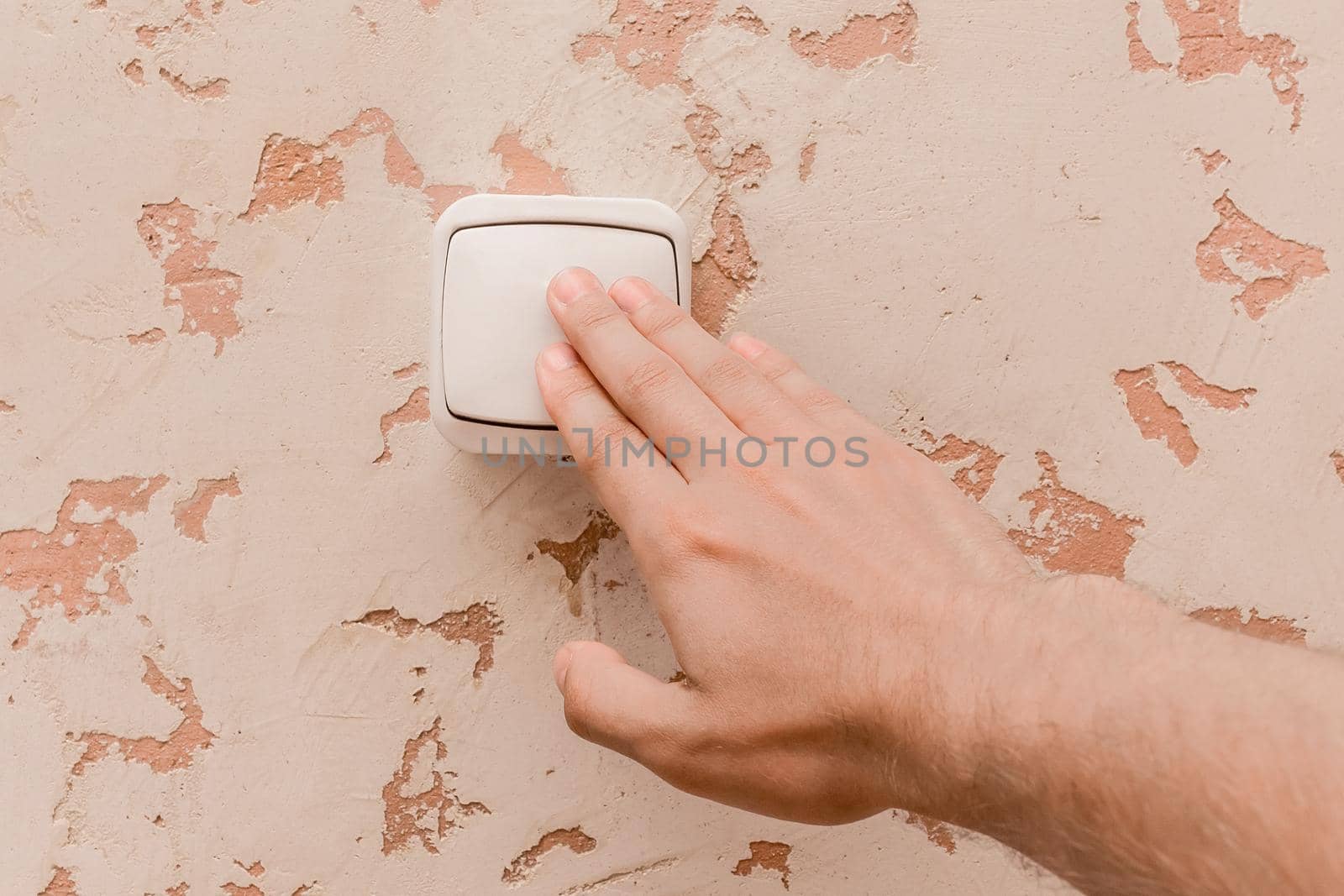 The guy's hand turns off the light with an electric switch in a modern room interior background by AYDO8