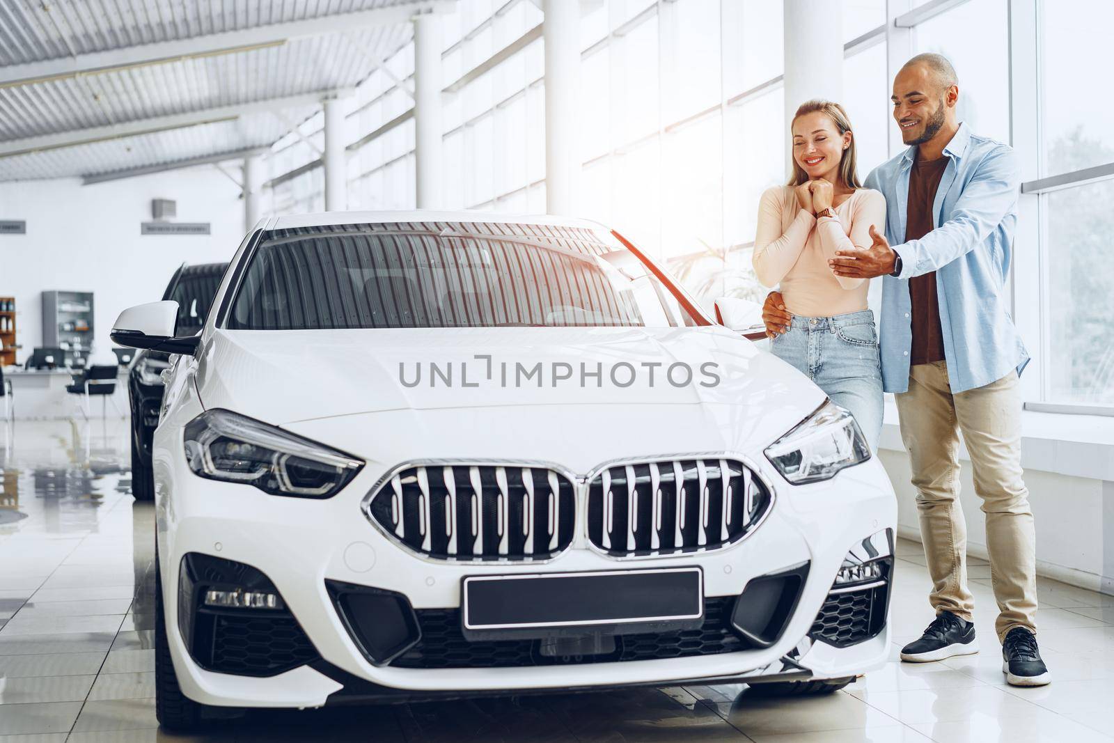 Young happy couple choosing a new car in car dealership